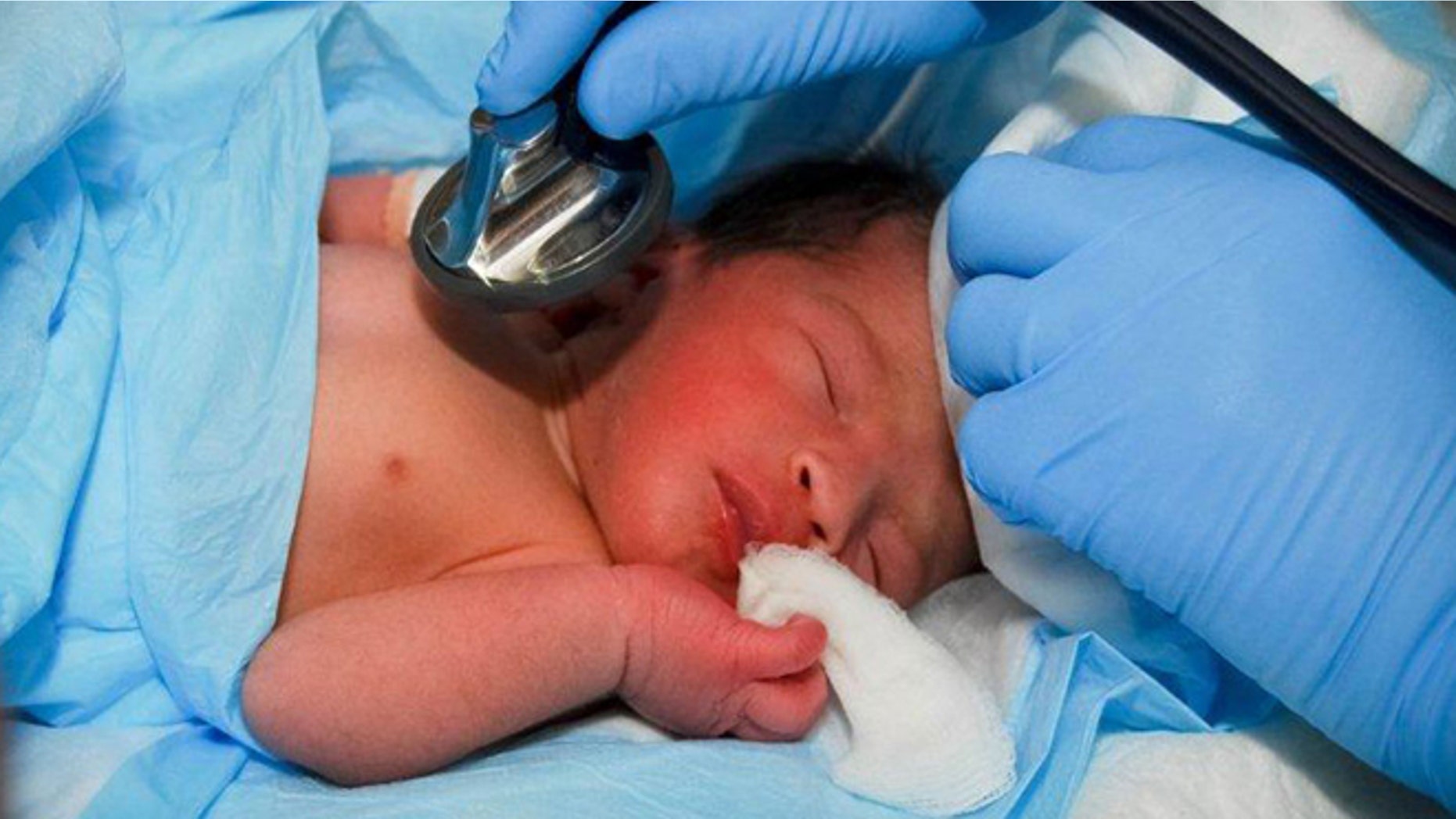 In this picture made available by the Operations Command of Poland's Defense Ministry in Warsaw, Poland, on Thursday, Sept. 20, 2012 , a newborn baby girl which Polish sappers found on Wednesday abandoned on the road of an armored patrol in southern Afghanistan receives attention in Waghez Afghanistan.