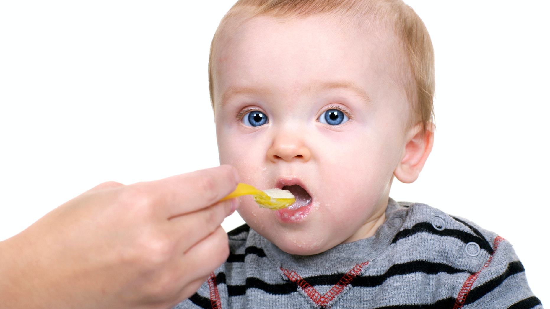 Baby being fed rice cereal.