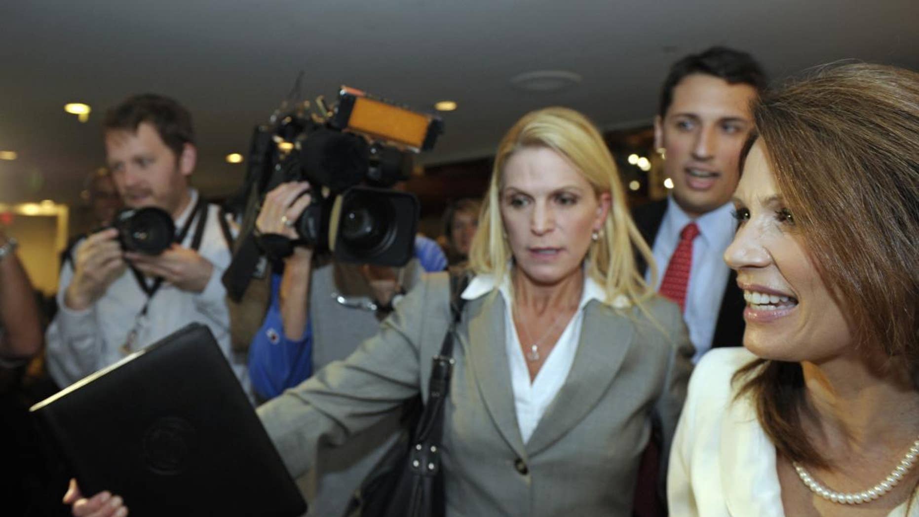 Republican presidential candidate, Rep. Michele Bachmann, R-Minn., right, is rushed past the news media as she departs a National Press Club luncheon in Washington, Thursday, July 28, 2011. . (AP Photo/Cliff Owen)