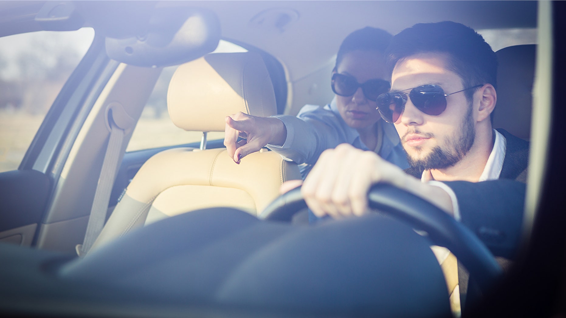 Business woman showing direction to chauffeur from the back of a car