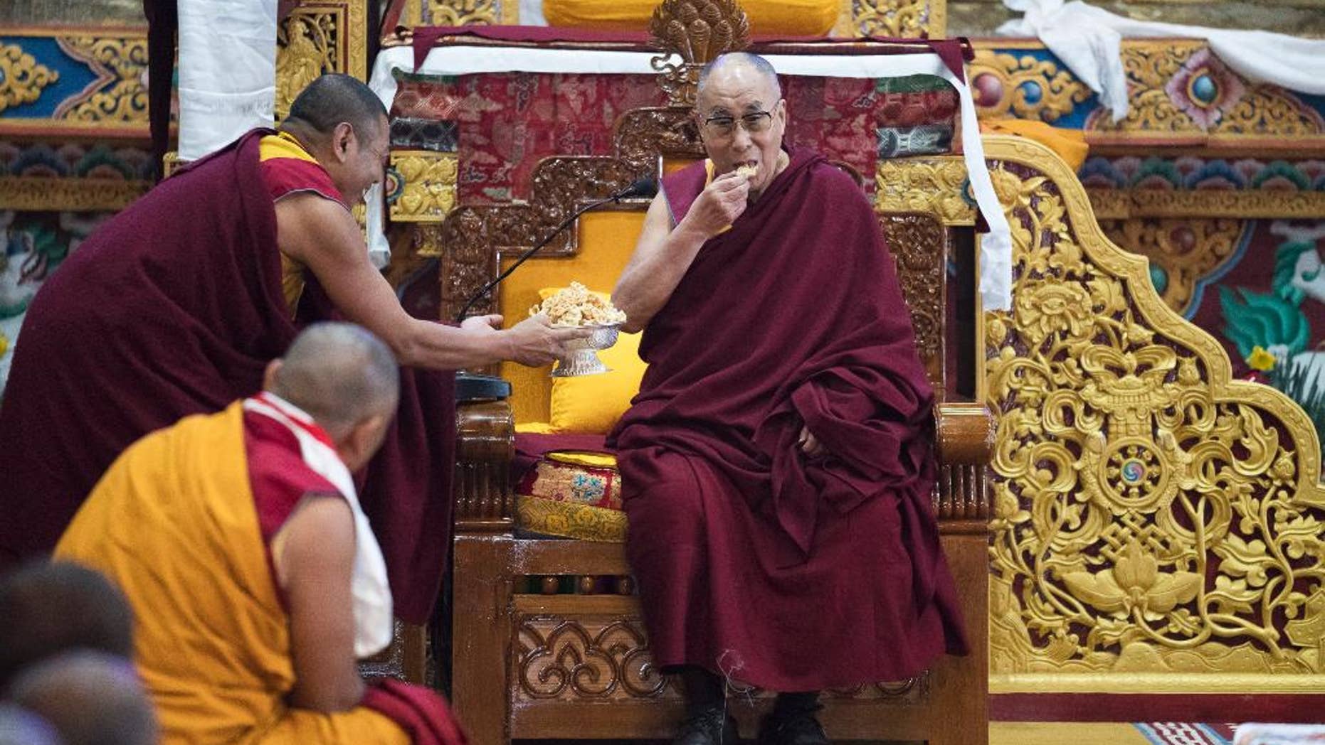 Tibetan spiritual leader the Dalai Lama eats traditional Tibetan cookies upon arrival at the monastery in Tawang, in the northeastern Indian state of Arunachal Pradesh, Friday, April 7, 2017. The visit to Arunachal Pradesh, which China also claims as its territory, has raised tensions between the nuclear-armed Asian neighbors. China's Foreign Ministry has said the visit "severely harms China's interests and the China-India relationship," while India has cautioned Beijing to stay out of its internal affairs. (AP Photo/ Tenzin Choejor)