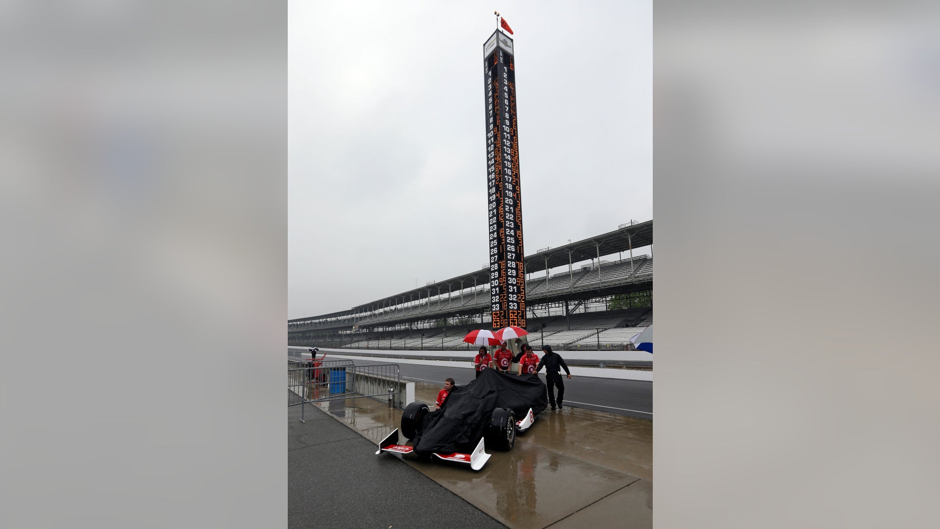 The crew of Scott Dixon, of New Zealand, pushes the car back to the garage area as rain halted track activity on the first day of qualifications for the Indianapolis 500 auto race at the Indianapolis Motor Speedway in Indianapolis, Saturday, May 18, 2013. (AP Photo/Darron Cummings)