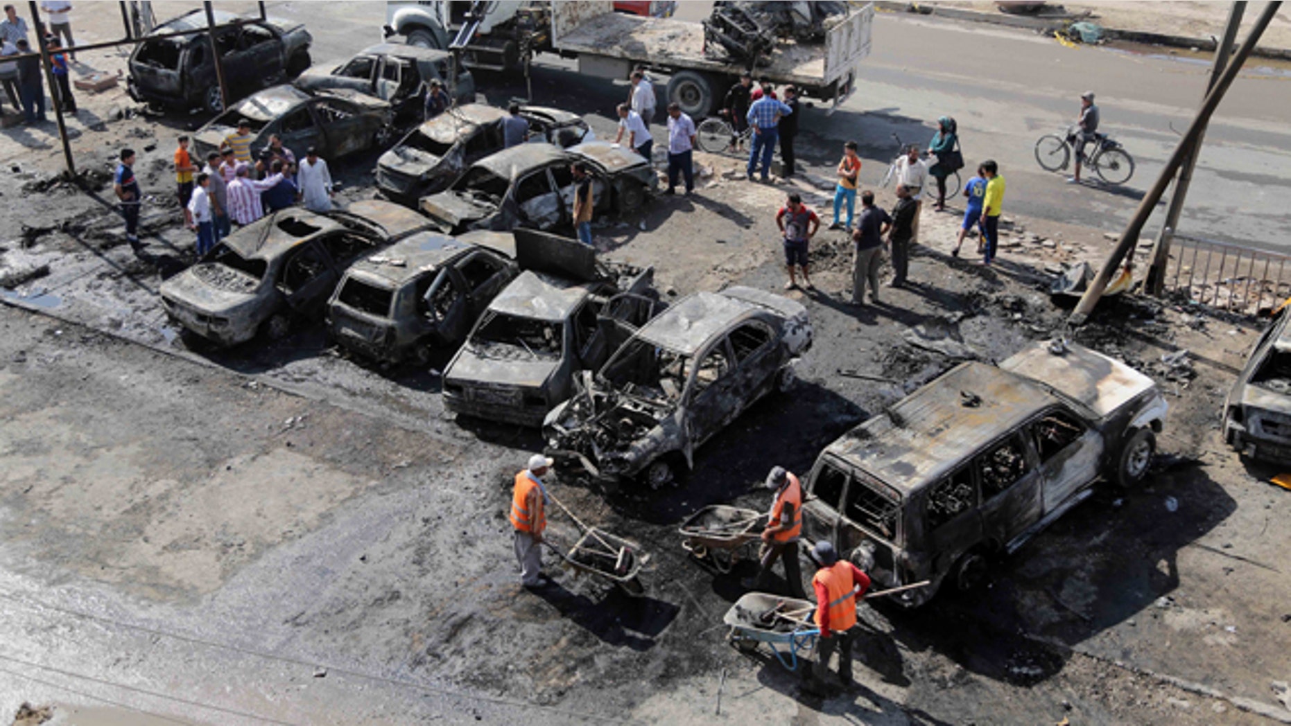 Oct. 27, 2013: Baghdad municipality workers clear debris while citizens inspect the site of a car bomb attack in a neighborhood of Baghdad, Iraq.