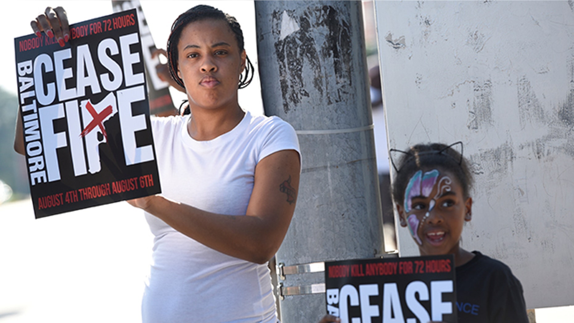 People hold signs at the "Stop the Violence" rally at the intersection of Edmondson Avenue and Wildwood Parkway during the 72 hour community-led Baltimore Ceasefire against gun violence in Baltimore, Maryland, U.S. August 4, 2017. REUTERS/Sait Serkan Gurbuz - RTS1AGR2