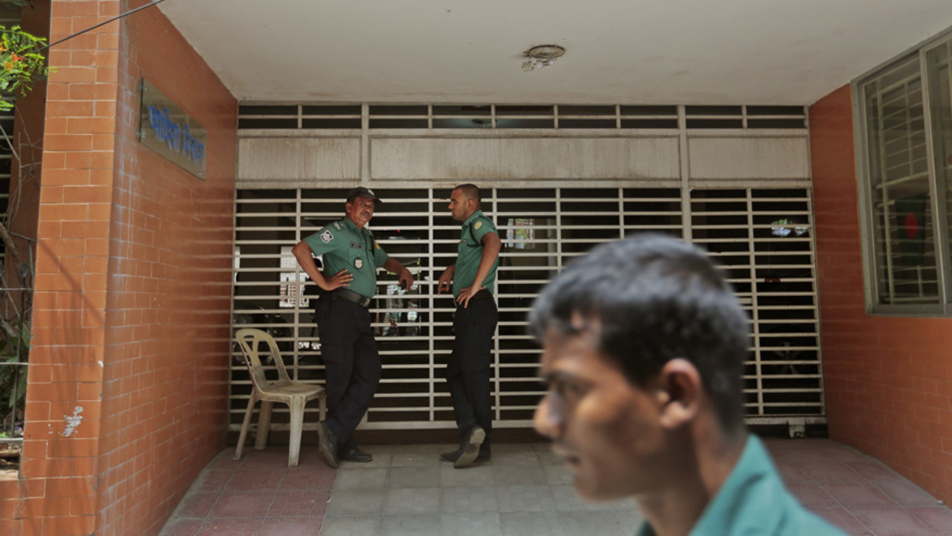 April 26, 2016: Bangladeshi policemen stand guard at the entrance to the building where two people were stabbed to death by unidentified assailants in Dhaka, Bangladesh.