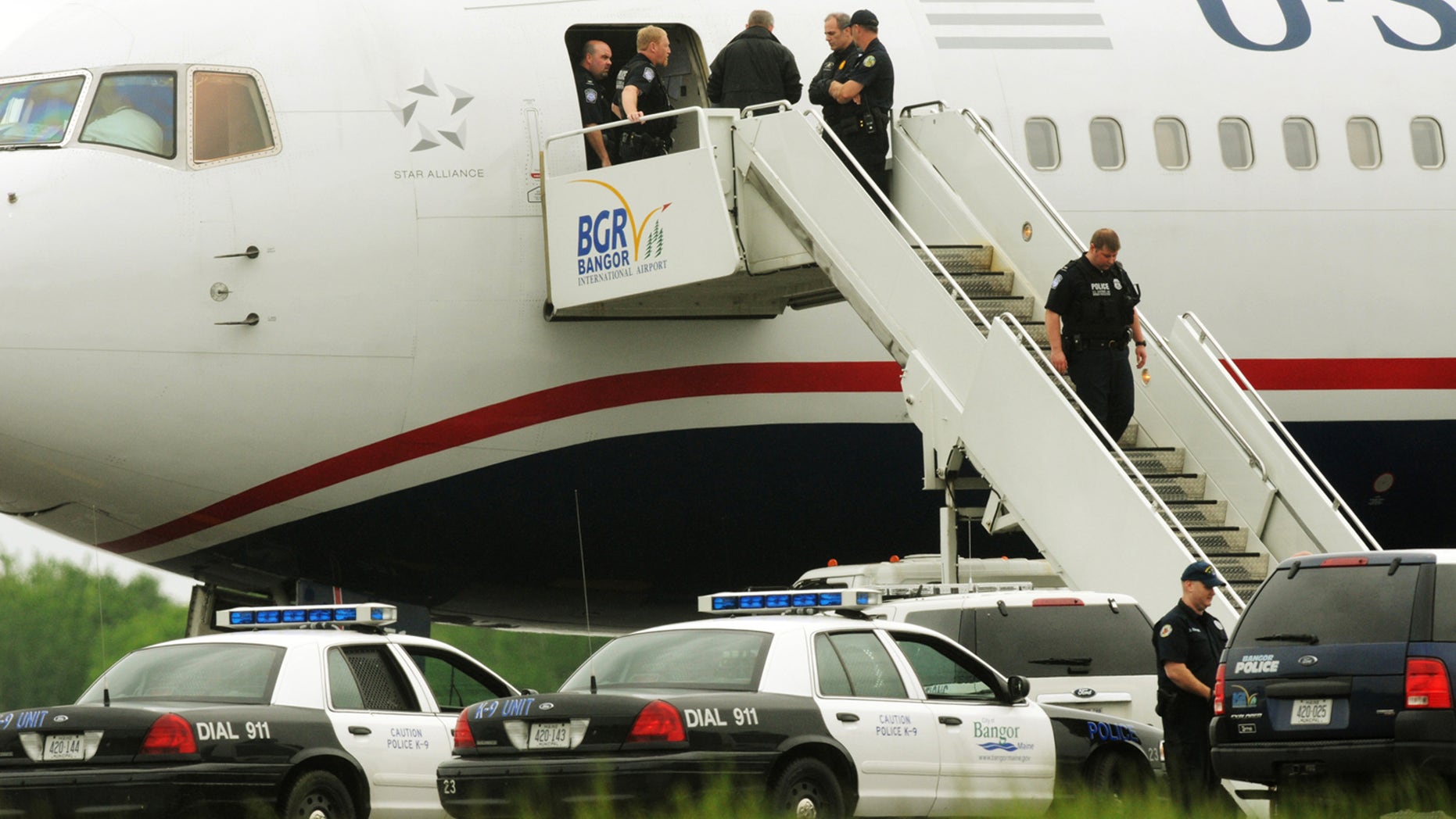 May 22, 2012: Law enforcement officials stand on a jet bridge and a passenger jet on the tarmac at Bangor International Airport, in Bangor, Me. The plane was diverted to Maine during its flight from France to Charlotte.