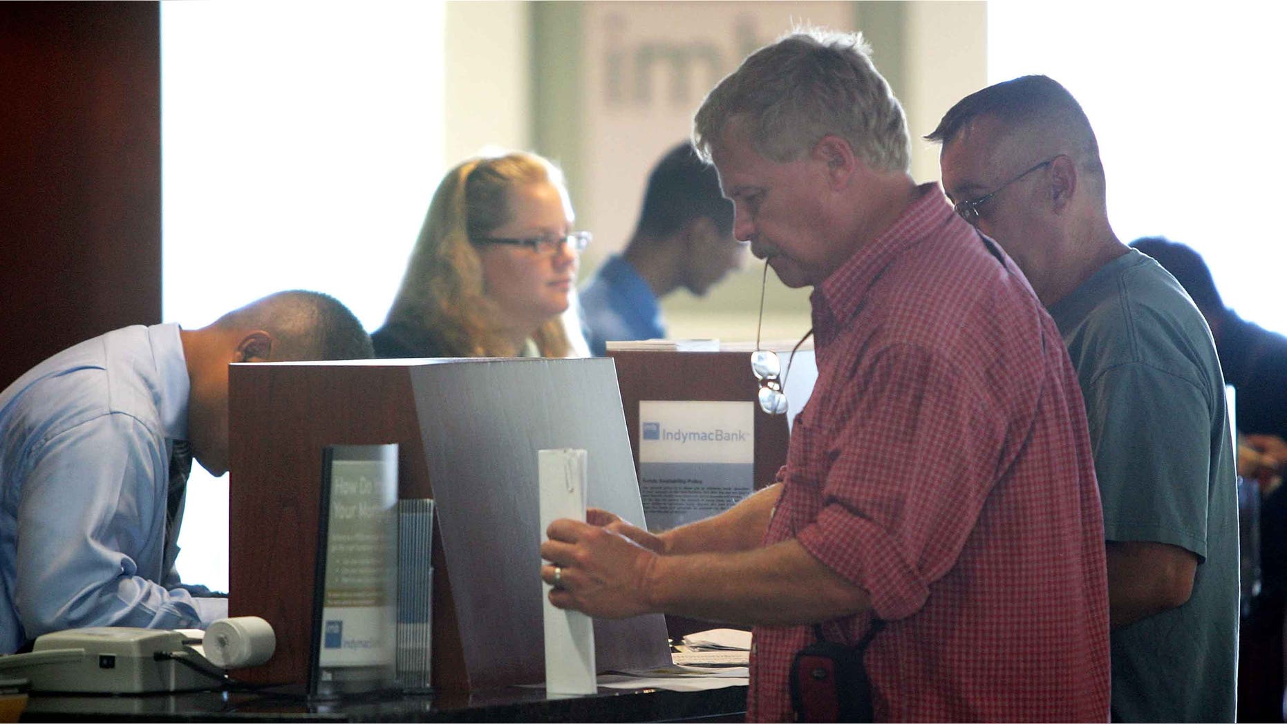 PASADENA, CA - JULY 14: Customers (R) carry out their transactions with tellers after waiting in line with hundreds of other nervous customers to get into an IndyMac Bank, open for the first time since the July 11 federal government takeover of the thrift, on July 14, 2008 in Pasadena, California. IndyMac, which was already in trouble because of it's subprime mortgages with people with bad or no credit history, was shut down three hours early on a Friday and remained closed over the weekend after customers withdrew $1.9 billion. Regulators say it is the second-largest bank failure ever in the US. As all 33 IndyMac branches reopen, customers with home-equity credit lines will reportedly find their accounts frozen while transactions involving deposit accounts will be conducted as normal under the name, IndyMac Federal Bank. Over the weekend, the Federal Reserve also worked on shoring up lenders Fannie Mae and Freddie Mac which control almost half of the national mortgage debt and are in danger of collapse as well. (Photo by David McNew/Getty Images)