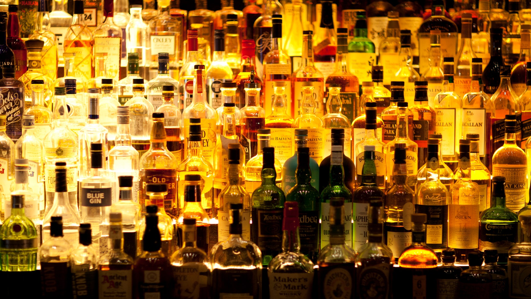 Various liquor bottles sitting behind bar, backlit