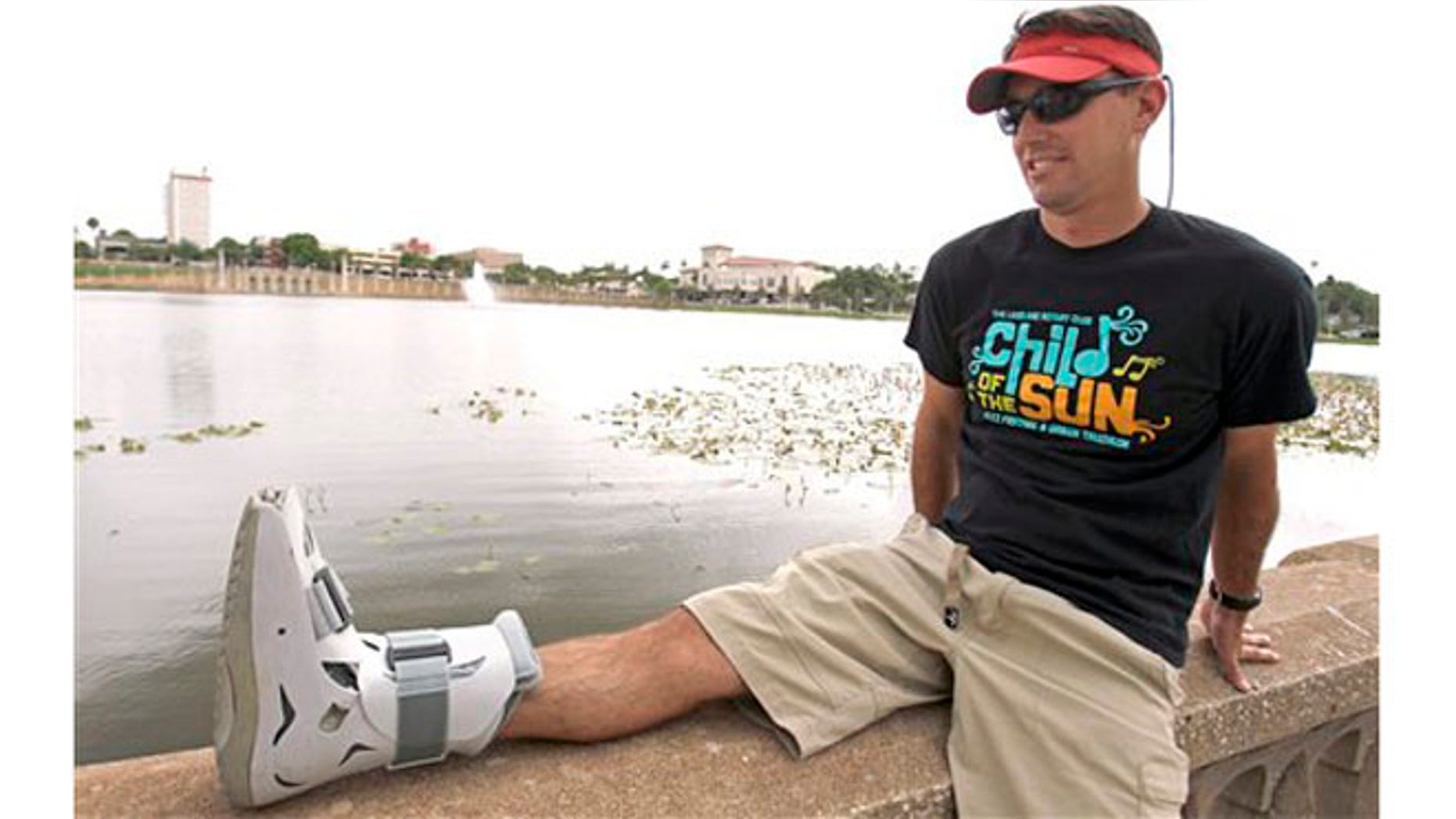 Greg Farris takes a break while wearing a protective boot as he helps set up for a weekend triathlon event in Lakeland, Fla. Farris injured his foot while running in barefoot running shoes.