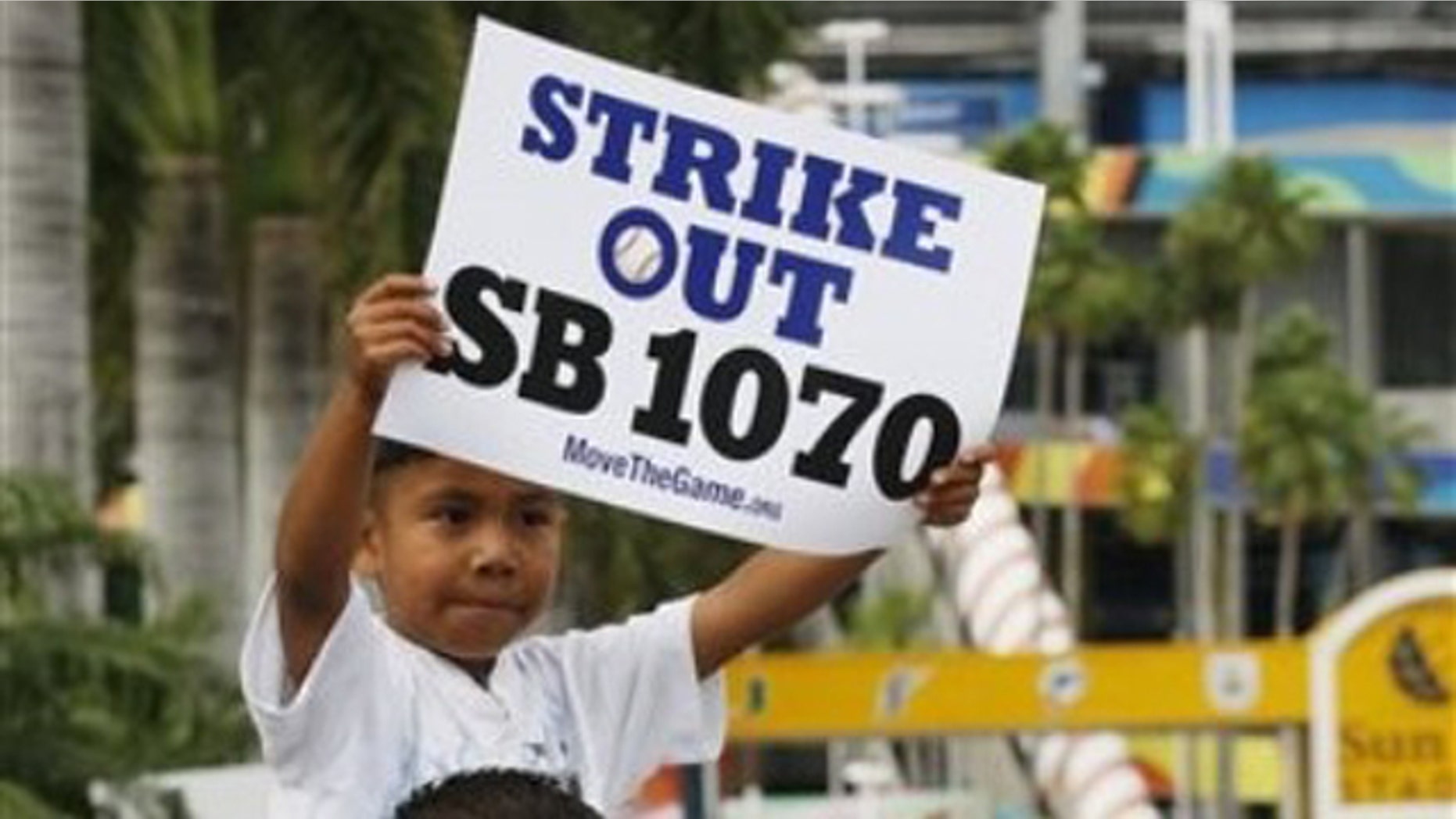 Elias Perez, 5, sits on the shoulders of Gerardo Reyes of Immokalee, Fla. , as they protest the Arizona Immigration Law SB 1070 outside Sun Life Stadium, before a baseball game between the Florida Marlins and the Arizona Diamondbacks, Monday, May 17, 2010 in Miami. (AP)