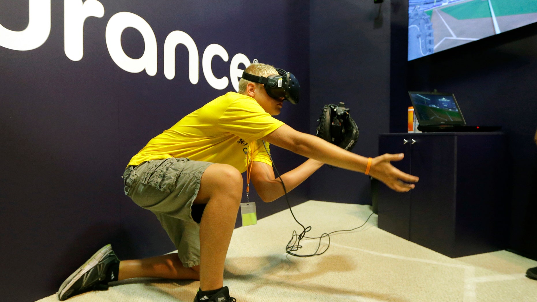 In this Friday, July 7, 2017, photo, Dennis Milman reaches to catch a virtual ball at the All-Star FanFest in Miami Beach, Fla. Virtual Reality baseball is a hit at the All-Star FanFest in Miami. Fans get to feel what it's like to be the San Francisco Giants' Buster Posey catching without the pain of snatching major league pitches at 86-to-93 mph. (AP Photo/Alan Diaz)