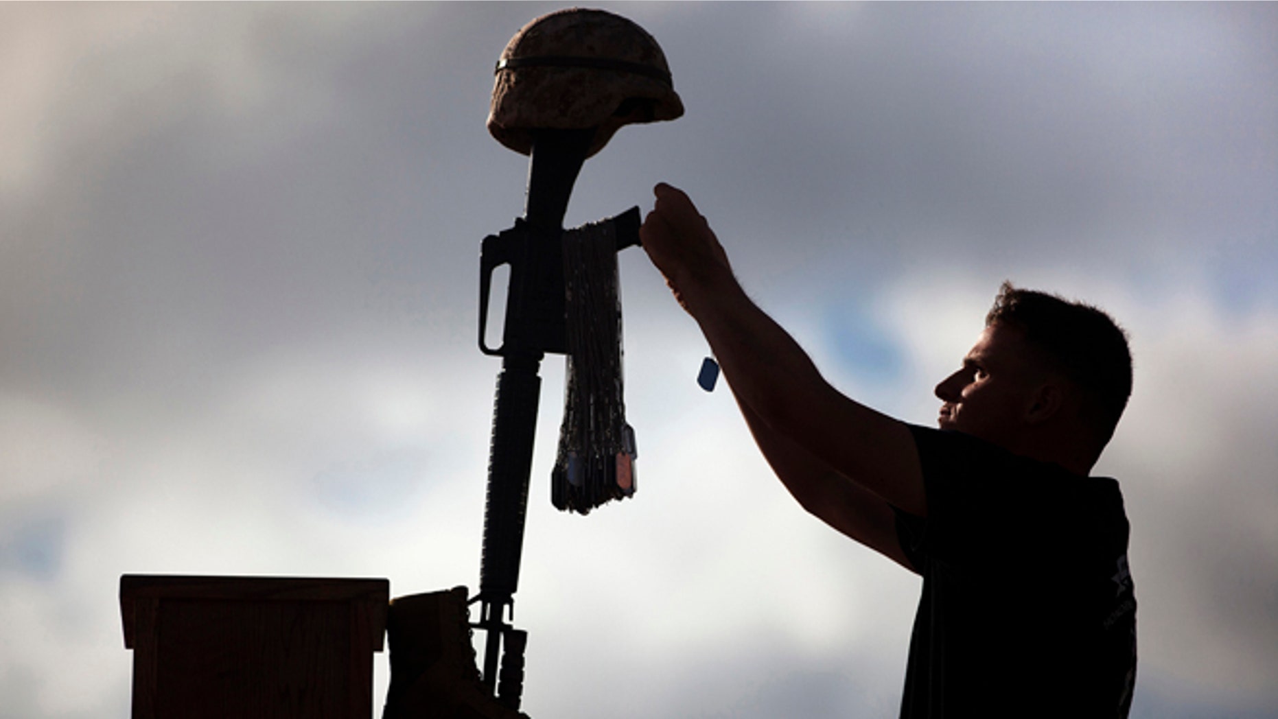 A US Marine places a dog tag of a fallen Marine atop a battlefield cross at a memorial in Hawaii in this 2012 photo.