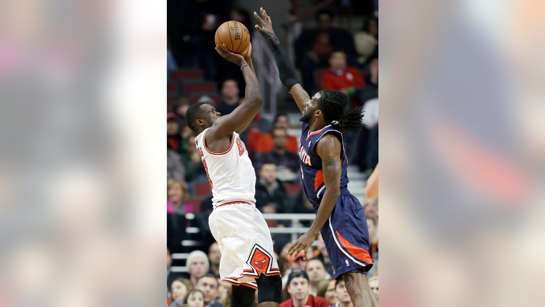 Chicago Bulls forward Luol Deng, left, shoots over Atlanta Hawks forward DeMarre Carroll during the first half of an NBA basketball game in Chicago on Saturday, Jan. 4, 2014. (AP Photo/Nam Y. Huh)