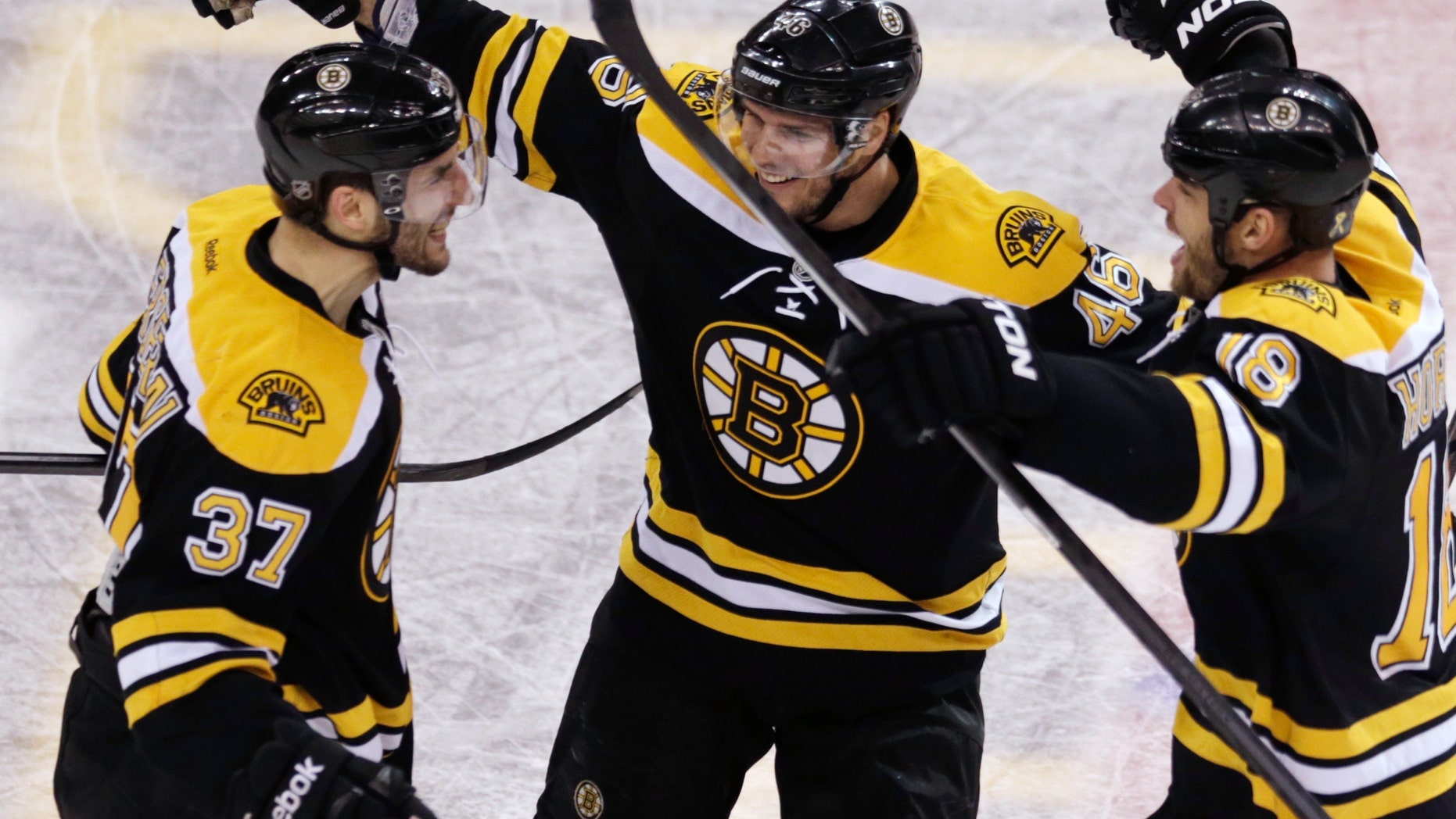 Boston Bruins center Patrice Bergeron, left, is congratulated by teammates David Krejci, center, and Nathan Horton, right, after his goal in the final minute of the third period, which tied the game 4-4 forcing overtime against the Toronto Maple Leafs, in Game 7 of their NHL hockey Stanley Cup playoff series in Boston, Monday, May 13, 2013. (AP Photo/Charles Krupa)