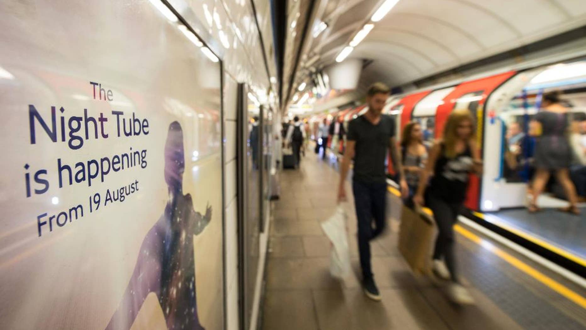 Passengers pass an advert for the night tube on a platform at Oxford Circus underground (tube) station, in London, Wednesday August 17, 2016. The London underground launches a 'Night Tube' service for the London mass transport system on Friday August 19. (Dominic Lipinski / PA via AP)