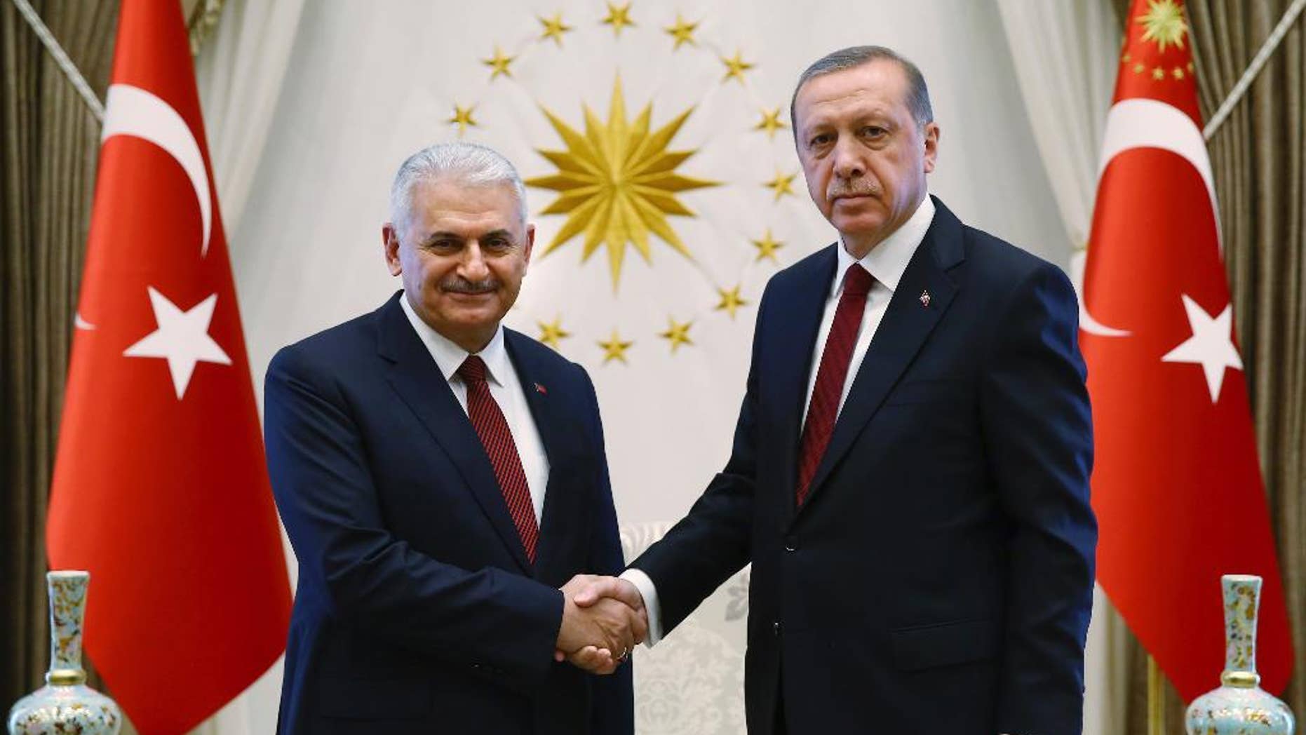 Turkey's President Recep Tayyip Erdogan, right and Turkey's incoming prime minister Binali Yildirim shake hands prior to the government's first cabinet meeting at the Presidential Palace in Ankara, Turkey, Wednesday, May 25, 2016. Erdogan had approved the new government formed by Yildirim, one of his most trusted allies, who immediately asserted the intention to institute constitutional reforms that would expand the powers of the presidency. (Presidential Press Service/Pool Photo via AP)