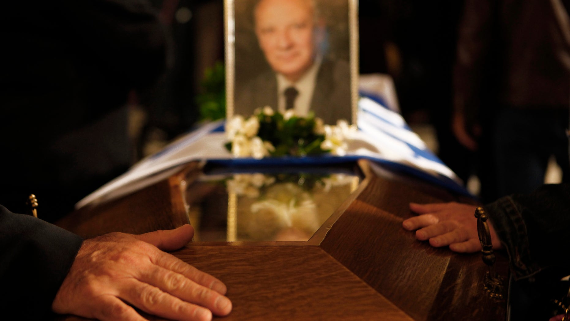 People touch the coffin of the former Cyprus President Glafcos Clerides, whose body lies in state at the Orthodox Christian Church of the Lord's Wisdom in capital Nicosia, Cyprus, Monday, Nov. 18, 2013. The politician's state funeral Tuesday will be held with honors befitting a sitting president and will be a public holiday. He was 94. (AP Photo/Petros Karadjias)