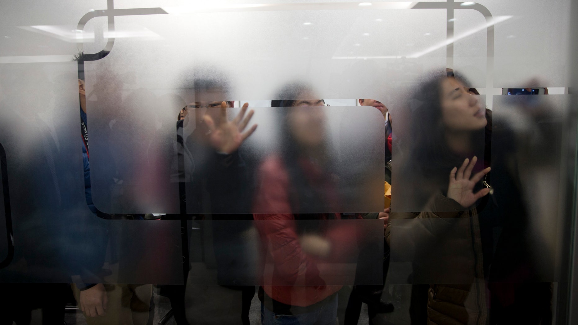 People try to get a view of U.S. Secretary of State John Kerry as he arrives for a tour of the Foton Cummins Engine plant in Beijing, China Saturday, Feb. 15, 2014. Kerry toured the plant and made remarks on climate change cooperation between the United States and China. (AP Photo/Evan Vucci, Pool)