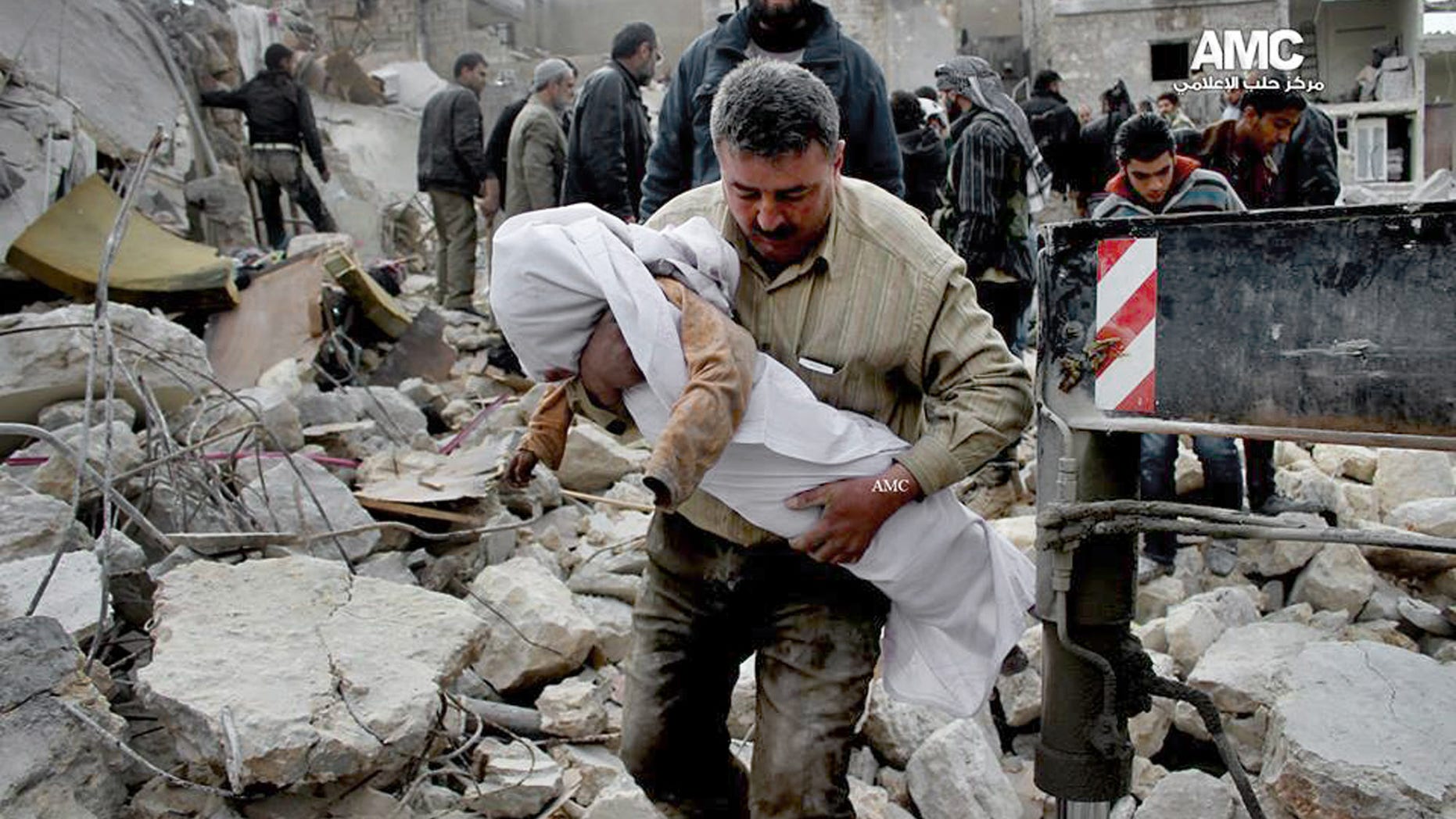 In this Wednesday, Jan. 29, 2014 citizen journalism image provided by Aleppo Media Center (AMC), an anti-Bashar Assad activist group, which has been authenticated based on its contents and other AP reporting, shows a Syrian man carrying the body of a child who was killed following a Syrian government airstrike in Aleppo, Syria. (AP Photo/Aleppo Media Center, AMC)