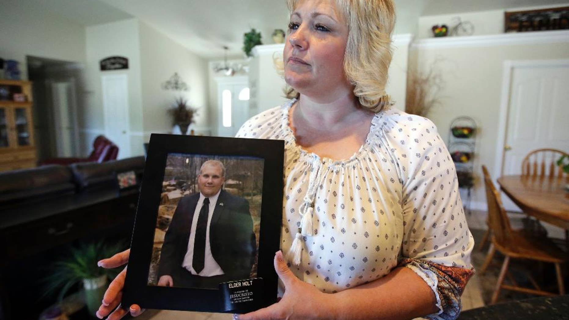 FILE - In this July 13, 2016 file photo, Laurie Holt holds a photograph of her son Joshua Holt at her home, in Riverton, Utah. Joshua Holt jailed in Venezuela since June has had his hopes for being reunited with his family for Christmas all but dashed with the fourth postponement of a preliminary hearing. Judge Elena Cassiani did not appear for a Tuesday, dec. 6, 2016 hearing, in which she was to rule on whether to dismiss the weapons charges against Holt. A new date was set for January. (AP Photo/Rick Bowmer, File)