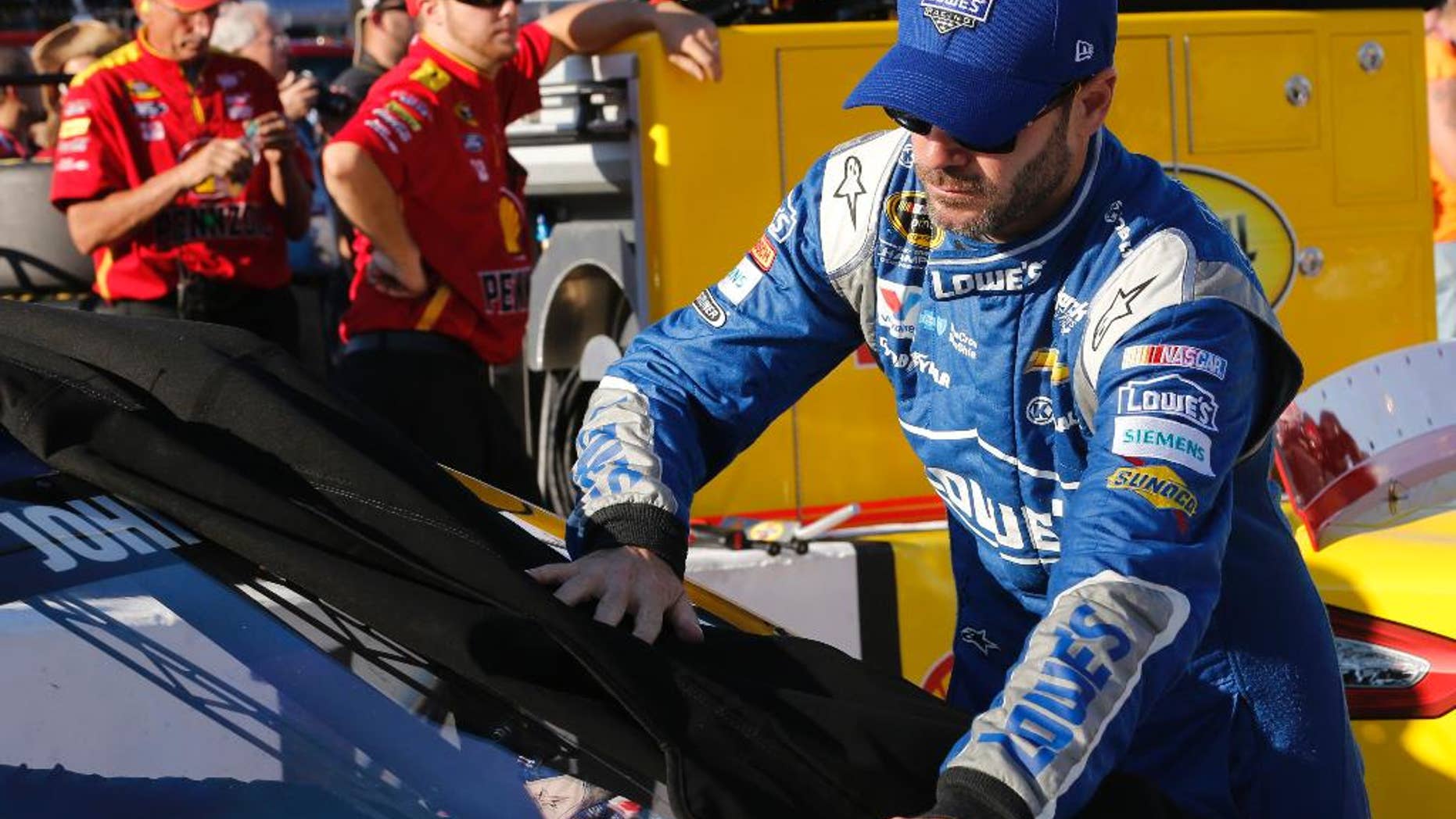 Jimmie Johnson takes a cover off his car prior to qualifying for Saturday's NASCAR Sprint Cup auto race at Richmond International Raceway in Richmond, Va., Friday, Sept. 11, 2015. (AP Photo/Steve Helber)