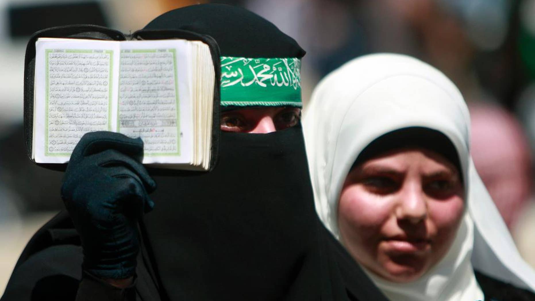 A Palestinian supporter of Hamas holds the Quran as others shout slogans against the Israeli military action in Gaza, during a demonstration in the West Bank town of Tulkarem town on Friday, Aug. 1, 2014. A Palestinian man was shot and killed during clashes with Israeli troops, following the demonstration in Tulkarem, Palestinian security sources said. (AP Photo/Mohammed Ballas)