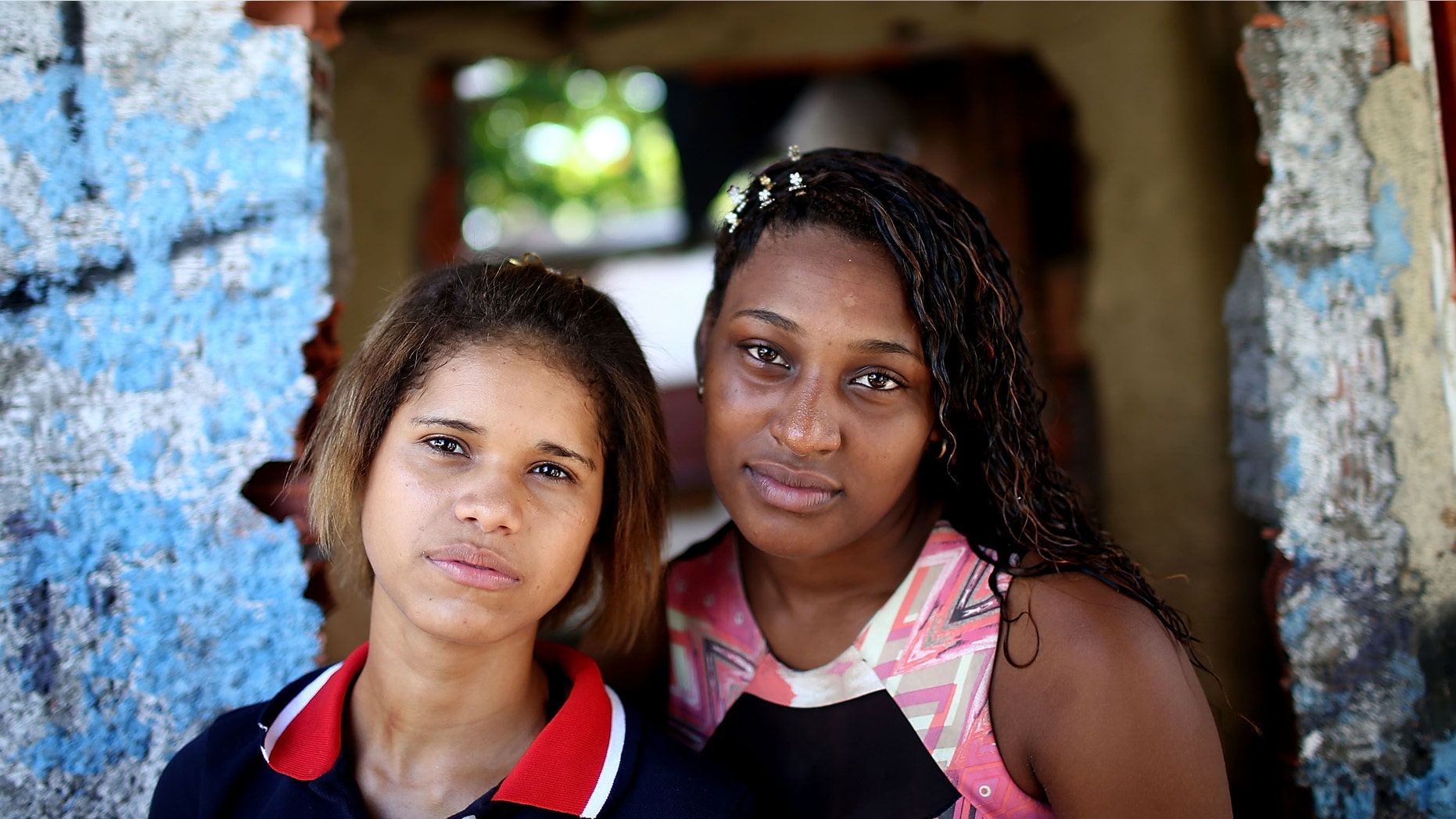 RIO DE JANEIRO, BRAZIL - APRIL 19: Young women pose in the occupied Complexo da Mare, one of the largest 'favela' complexes in Rio, on April 19, 2014 in Rio de Janeiro, Brazil. The Brazilian government has deployed nearly 3,000 federal troops to occupy the group of violence-plagued slums ahead of the June 12 start of the 2014 FIFA World Cup. The group of 16 communities house around 130,000 residents and had been dominated by drug gangs and militias. Mare is located close to Rio's international airport and has been mentioned as a likely pacification target for the police amid the city's efforts to improve security ahead of the 2014 FIFA World Cup and Rio 2016 Olympic Games. (Photo by Mario Tama/Getty Images)