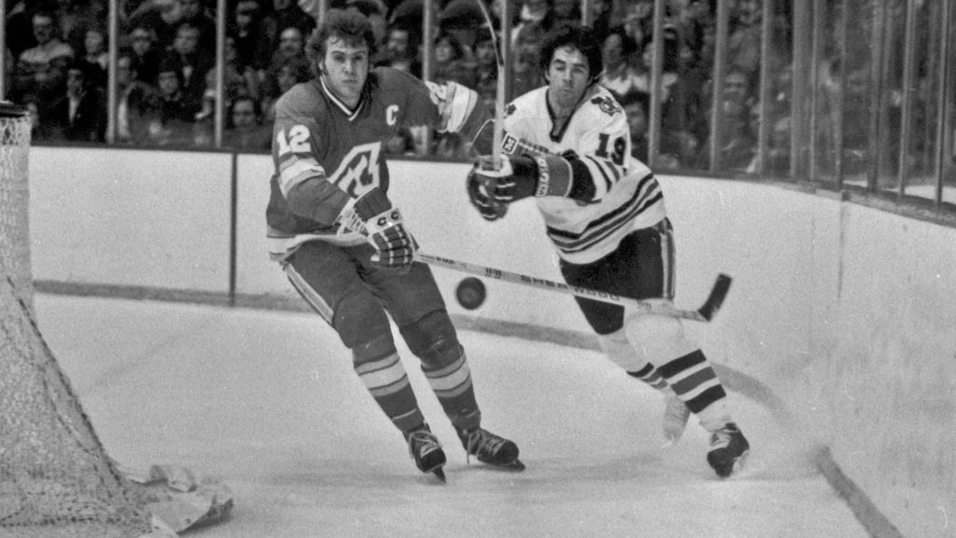 FILE - In this Dec. 18, 1977, file photo, Atlanta Flames' Tom Lysiak, left, and Chicago Blackhawks' Dale Tallon chase after the puck during the first period of an NHL hockey game in Chicago. Lysiak, a three-time NHL All-Star who played 13 NHL seasons with the Flames and Blackhawks, has died of leukemia at the age of 63. His daughter, Jessie Lysiak Braun, confirmed on Twitter that he died Monday, May 30, 2016. (AP Photo/Fred Jewell, File)
