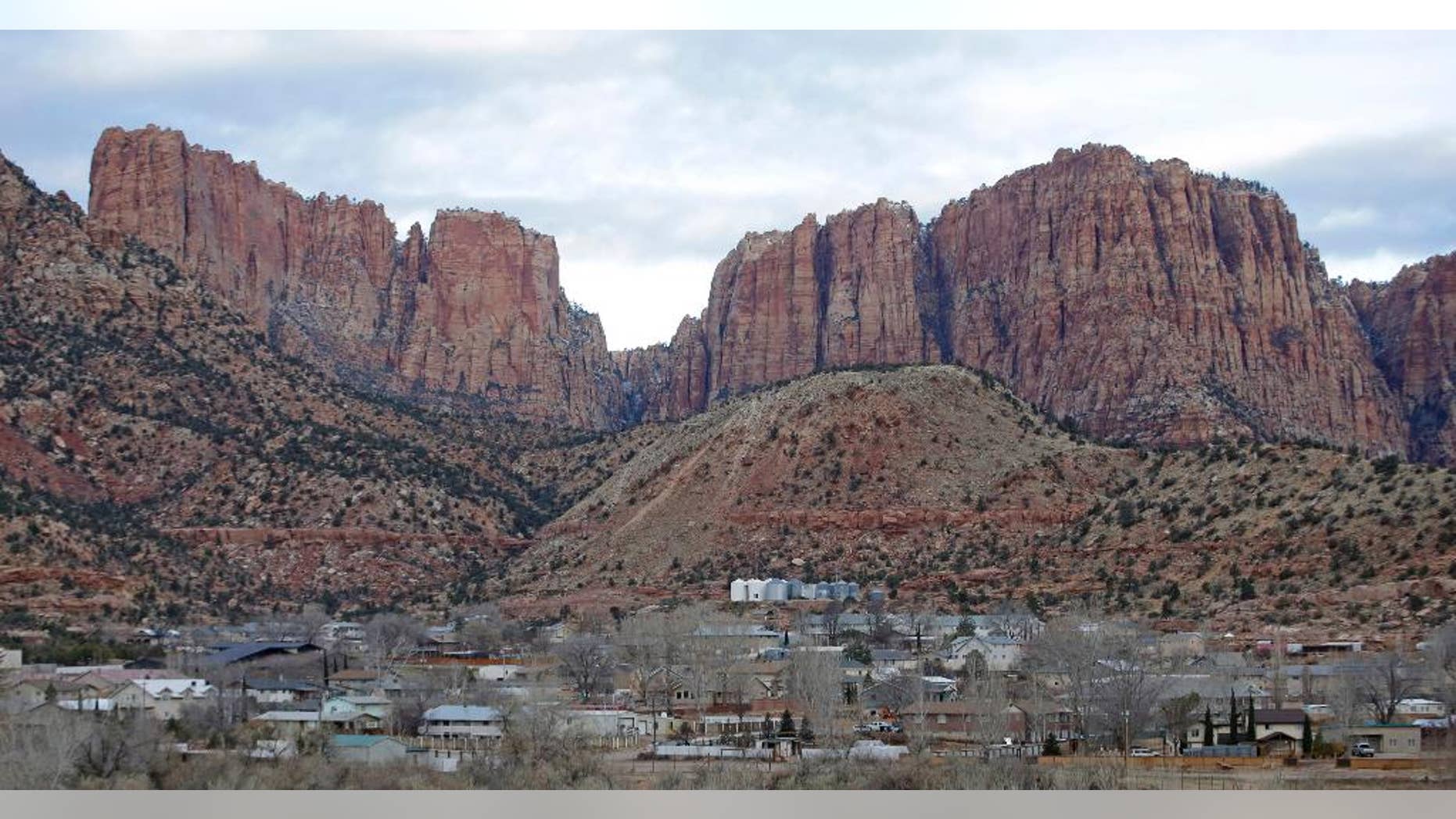 FILE - This Dec. 16, 2014, file photo, shows Hildale, Utah, sitting at the base of Red Rock Cliff mountains, with its sister city, Colorado City, Ariz., in the foreground. The federal government's bid to dismantle the police department in a polygamous community on the Arizona-Utah border has been rejected by a judge as too drastic and expensive. But the towns will still be under court supervision for the next decade as punishment in a religious discrimination case. (AP Photo/Rick Bowmer, File)