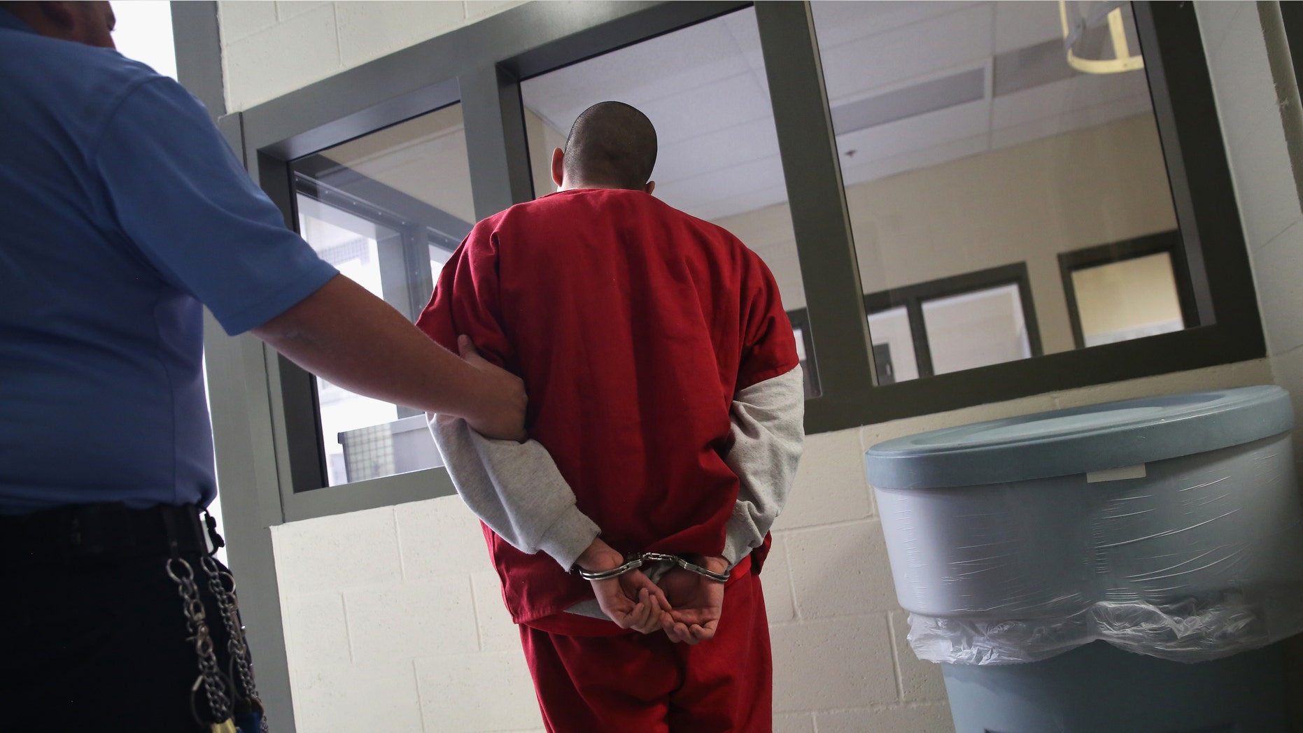 ADELANTO, CA - NOVEMBER 15: A guard escorts an immigrant detainee from his 'segregation cell' back into the general population at the Adelanto Detention Facility on November 15, 2013 in Adelanto, California. Most detainees in segregation cells are sent there for fighting with other immigrants, according to guards. The facility, the largest and newest Immigration and Customs Enforcement (ICE), detention center in California, houses an average of 1,100 immigrants in custody pending a decision in their immigration cases or awaiting deportation. The average stay for a detainee is 29 days. The facility is managed by the private GEO Group. ICE detains an average of 33,000 undocumented immigrants in more than 400 facilities nationwide. (Photo by John Moore/Getty Images)