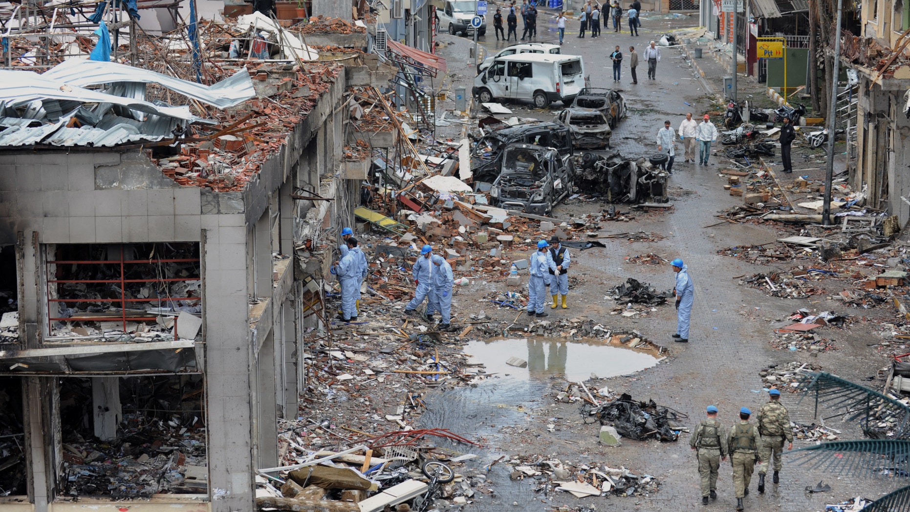 Police forensic officers work as army commandos patrol the area at the scene at one of the Saturday explosion sites that killed 46 and injured about 50 others, in Reyhanli, near Turkey's border with Syria, Sunday, May 12, 2013. The bombings on Saturday marked the biggest incident of cross-border violence since the start of Syria's bloody civil war and has the raised fear of Turkey being pulled deeper into the conflict.(AP Photo)