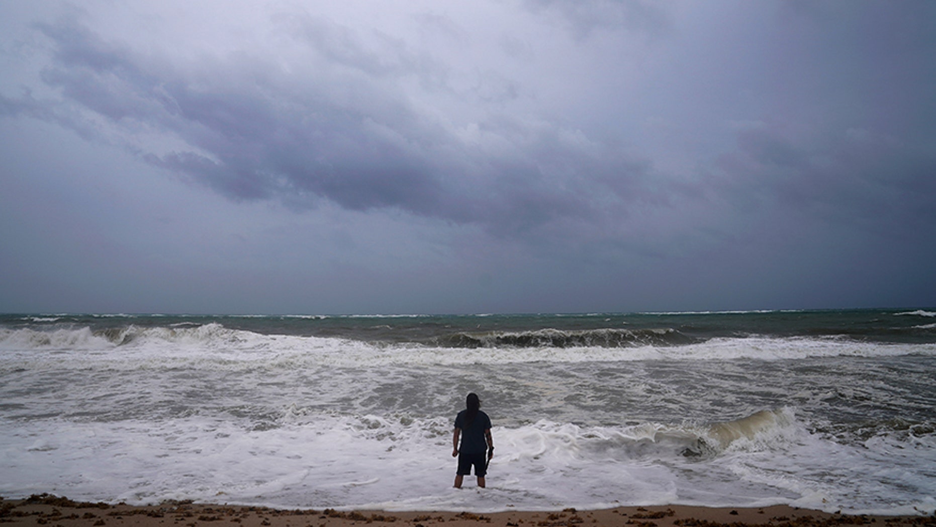 A man stands in the water at the beach ahead of Hurricane Irma's expected arrival in Fort Lauderdale, Florida, U.S., September 9, 2017. REUTERS/Carlo Allegri - RC12C86B5960