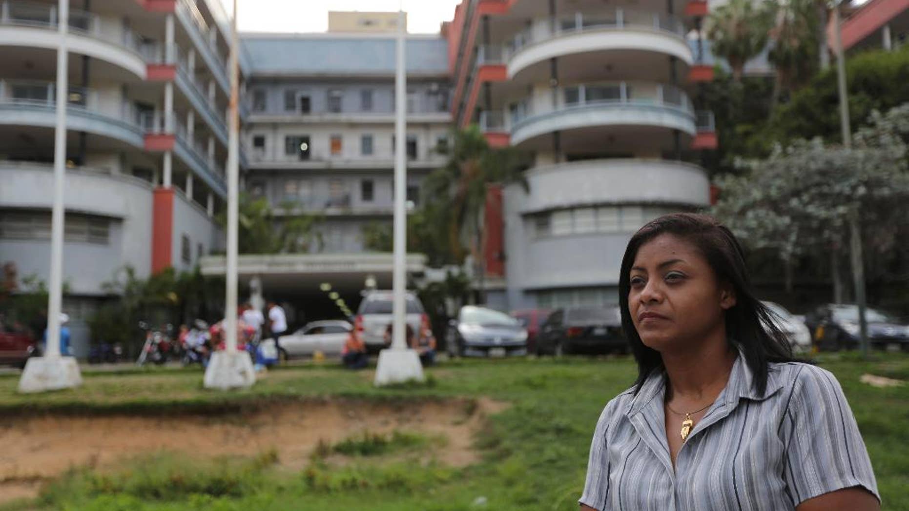 Carmen Bolivar, a University Hospital nurse, poses for a photo outside of the Hospital in Caracas, Venezuela, Wednesday, Aug. 13, 2014. Last June Carmen stood paralyzed by fear next to a patient’s brother as a gunman walked in on them. University Hospital, a sprawling, poorly maintained building that resembles a noisy bus station, guards still go unarmed, there is no surveillance system and a worn sign reading “No entrance” is the only thing stopping a person from walking into the operating area. Security workers say they would run if confronted by an armed intruder. (AP Photo/Ariana Cubillos)