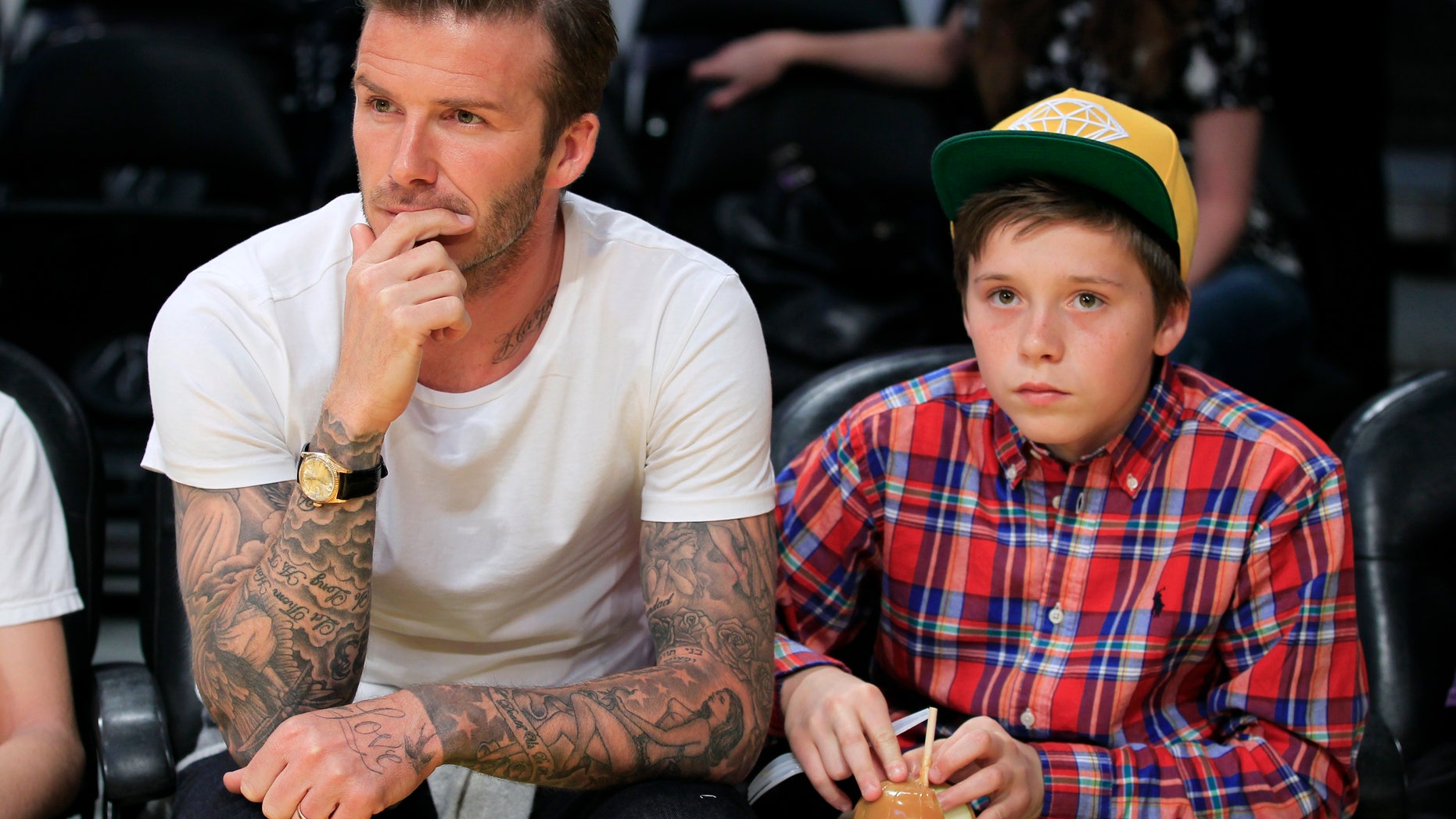 March 4, 2012. Soccer star David Beckham (L) and his son Brooklyn watch the Los Angeles Lakers play the Miami Heat in their NBA basketball game in Los Angeles, California.