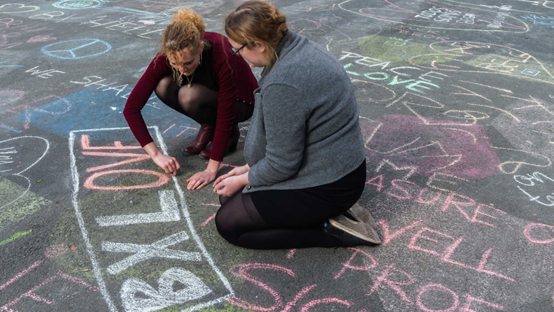 March 22, 2016: Two people write solidarity messages in chalk outside the stock exchange in Brussels.