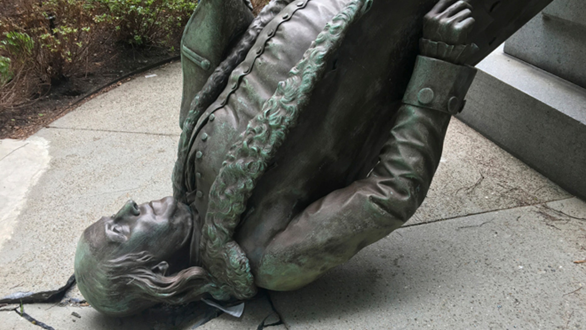 In this photo released by the City of Boston Mayor's office, a statue of Benjamin Franklin lies on the concrete outside where it landed when knocked off its pedestal outside Old City Hall