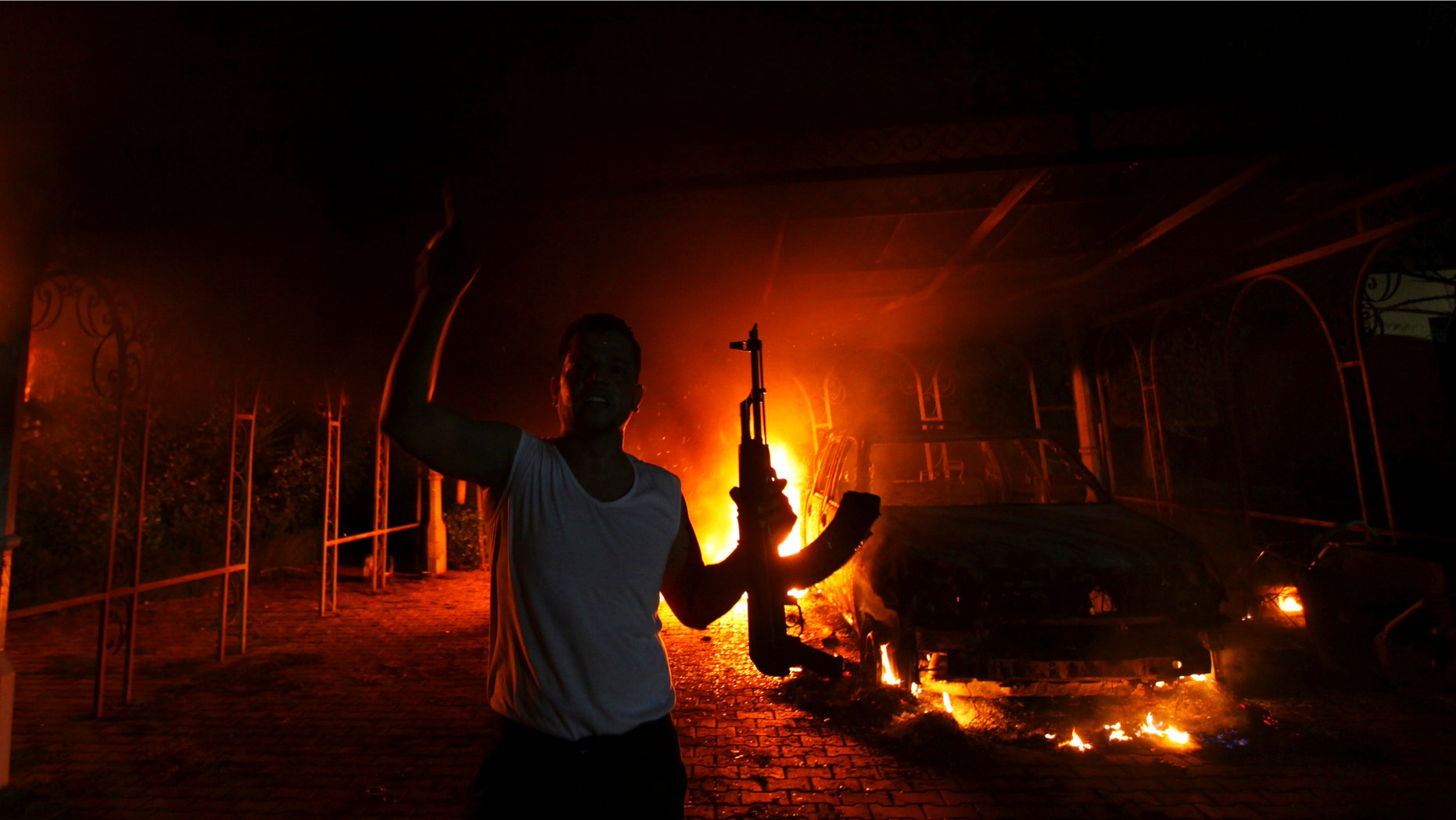A protester reacts as the U.S. Consulate in Benghazi is seen in flames during a protest by an armed group said to have been protesting a film being produced in the United States September 11, 2012.