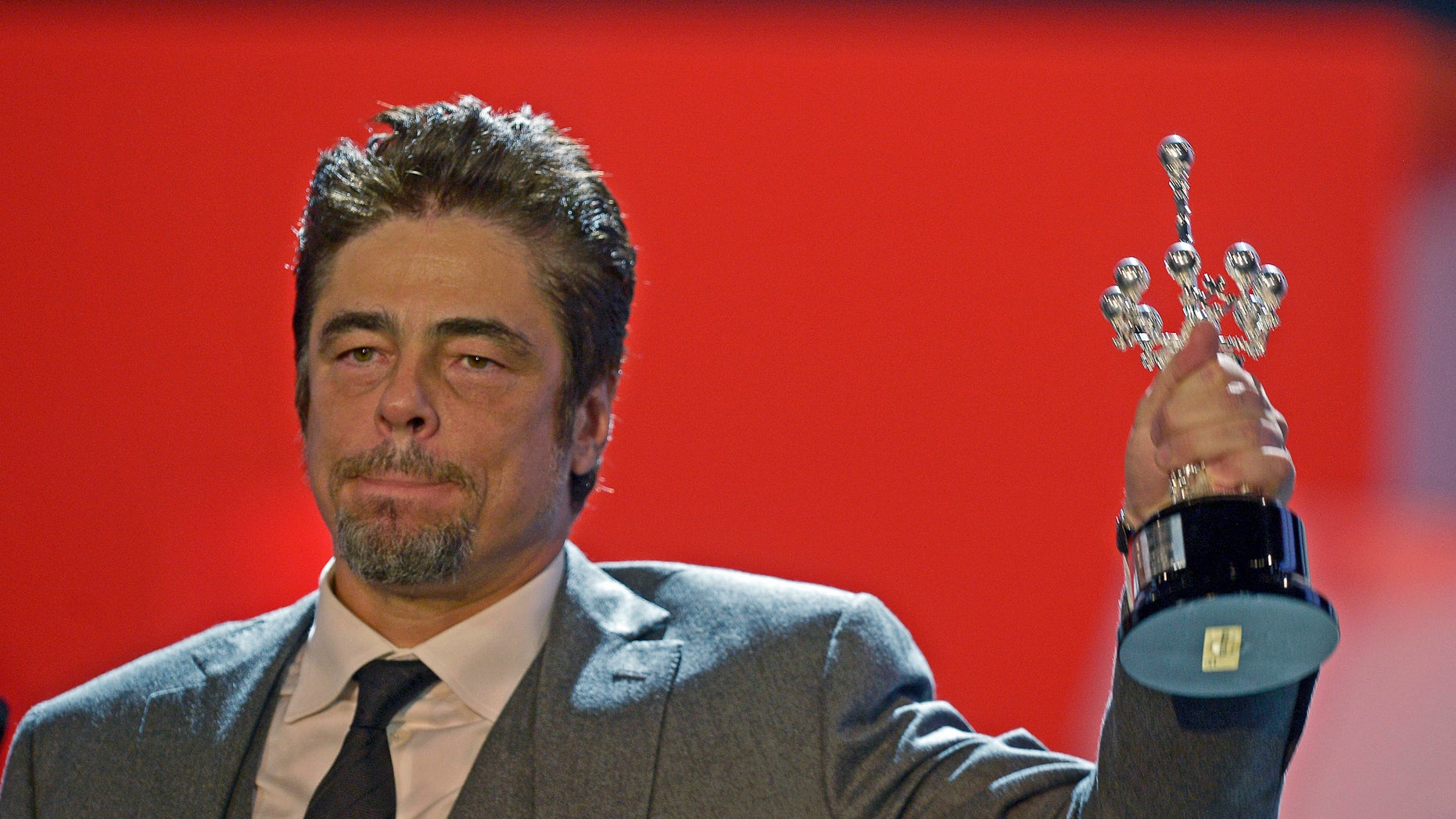 September 26, 2014. Puerto Rican actor Benicio Del Toro holds up his trophy after receiving the Donostia Award for career achievement on the eighth day of the 62nd San Sebastian Film Festival.