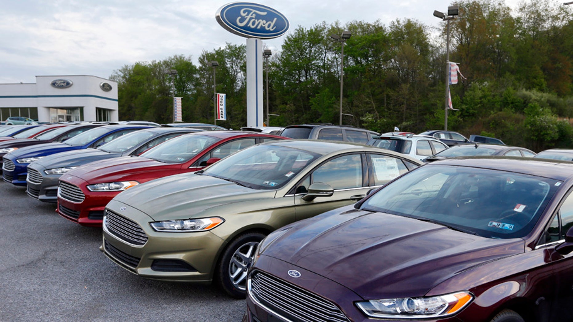 In this Wednesday, May 8, 2013 photo, new 2013 Ford Fusions are seen at an automobile dealer in Zelienople, Pa. U.S. auto sales slowed slightly in June 2014 but still maintained a healthy pace despite a record-setting string of safety recalls at General Motors and a slowdown in truck sales at Ford. Ford's U.S. sales chief John Felice said sales picked up at the end of June as automakers started promoting Independence Day sales. (AP Photo/Keith Srakocic)