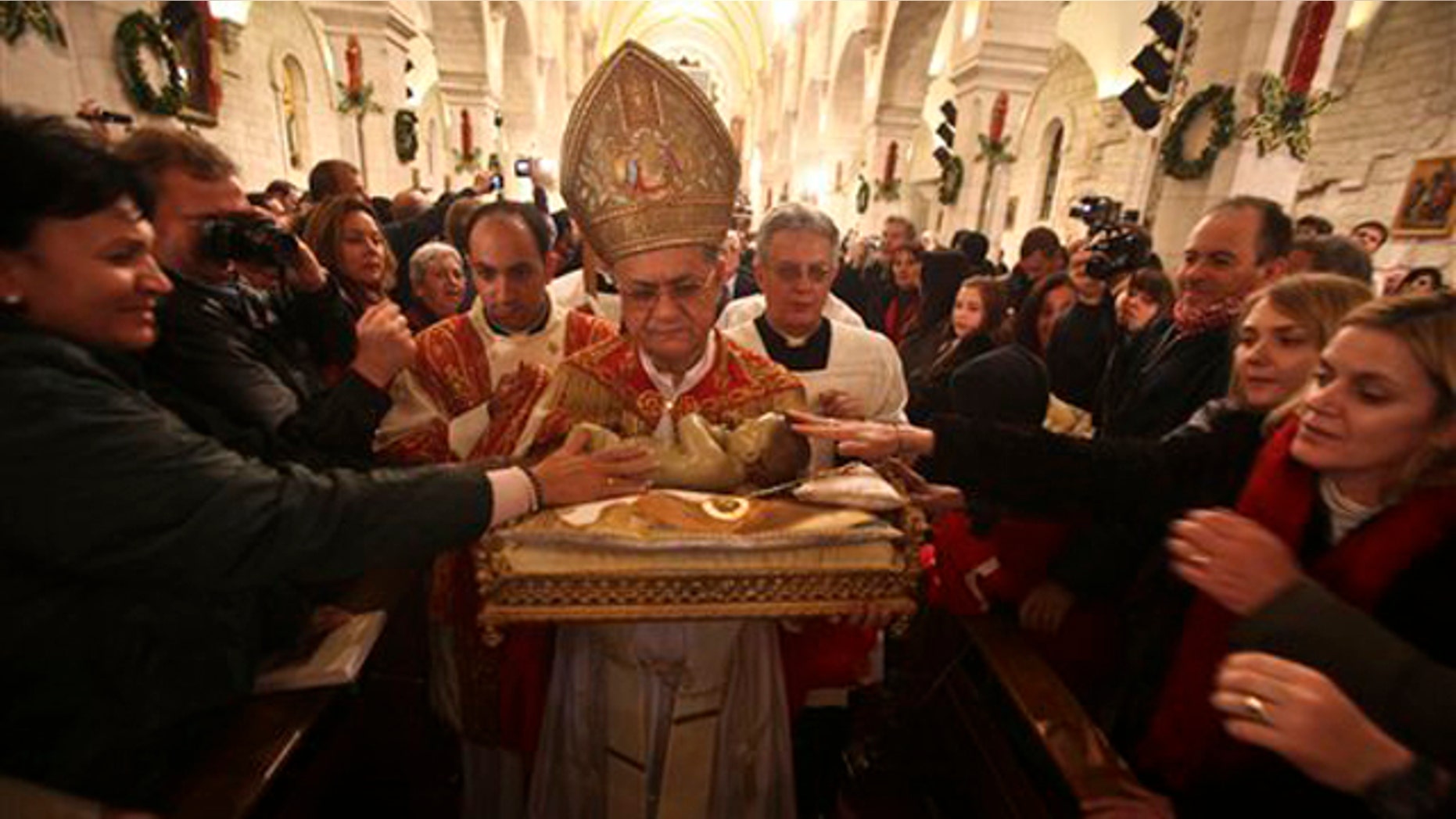 Dec. 25, 2010: Latin Patriarch of Jerusalem Fouad Twal carries the statuette of baby Jesus during the midnight Mass ceremony which marks the beginning of Christmas Day at the Church of the Nativity in the West Bank town of Bethlehem.