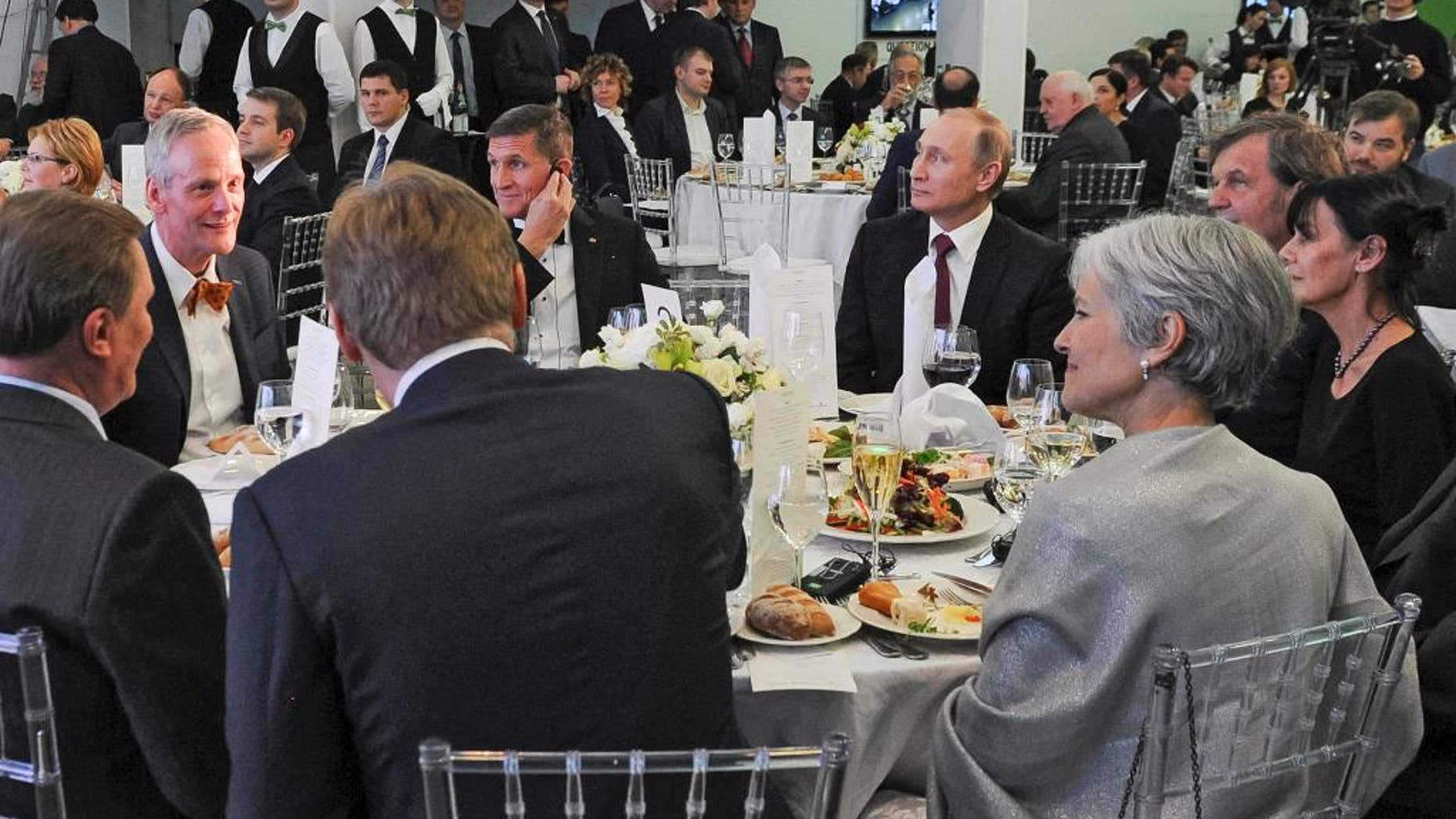 FILE- In this file photo taken on Thursday, Dec. 10, 2015, Russian President Vladimir Putin, center right, with retired U.S. Lt. Gen. Michael T. Flynn, center left, and Serbian filmmaker Emir Kusturica, obscured second right, attend an exhibition marking the 10th anniversary of RT (Russia Today) 24-hour English-language TV news channel in Moscow, Russia. Flynn is widely reported Thursday Nov. 17, 2016, to be a potential contender to become national security advisor to U.S. president elect Donald Trump, although his appointment may be controversial. (Mikhail Klimentyev/Sputnik, Kremlin Pool Photo via AP, file)
