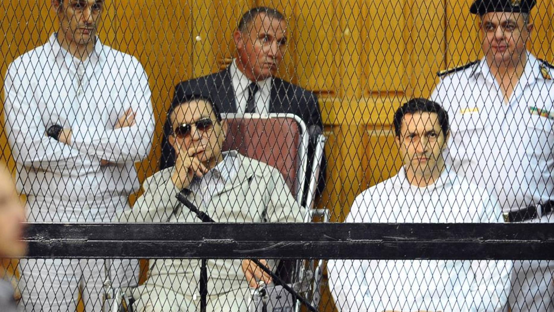 FILE - In this file photo taken Saturday, Sept. 14, 2013, former Egyptian President Hosni Mubarak, seated left, and his two sons, Gamal Mubarak, far left, and Alaa Mubarak attend a hearing in a courtroom at the Police Academy, Cairo, Egypt. The sons of Mubarak were ordered released on bail Thursday, Jan. 22, 2015, pending a retrial in the last case that was keeping them behind bars, opening the door for the release of the two for the first time since they were incarcerated in the wake of their father’s ouster in 2011. (AP Photo/Mohammed al-Law, File)