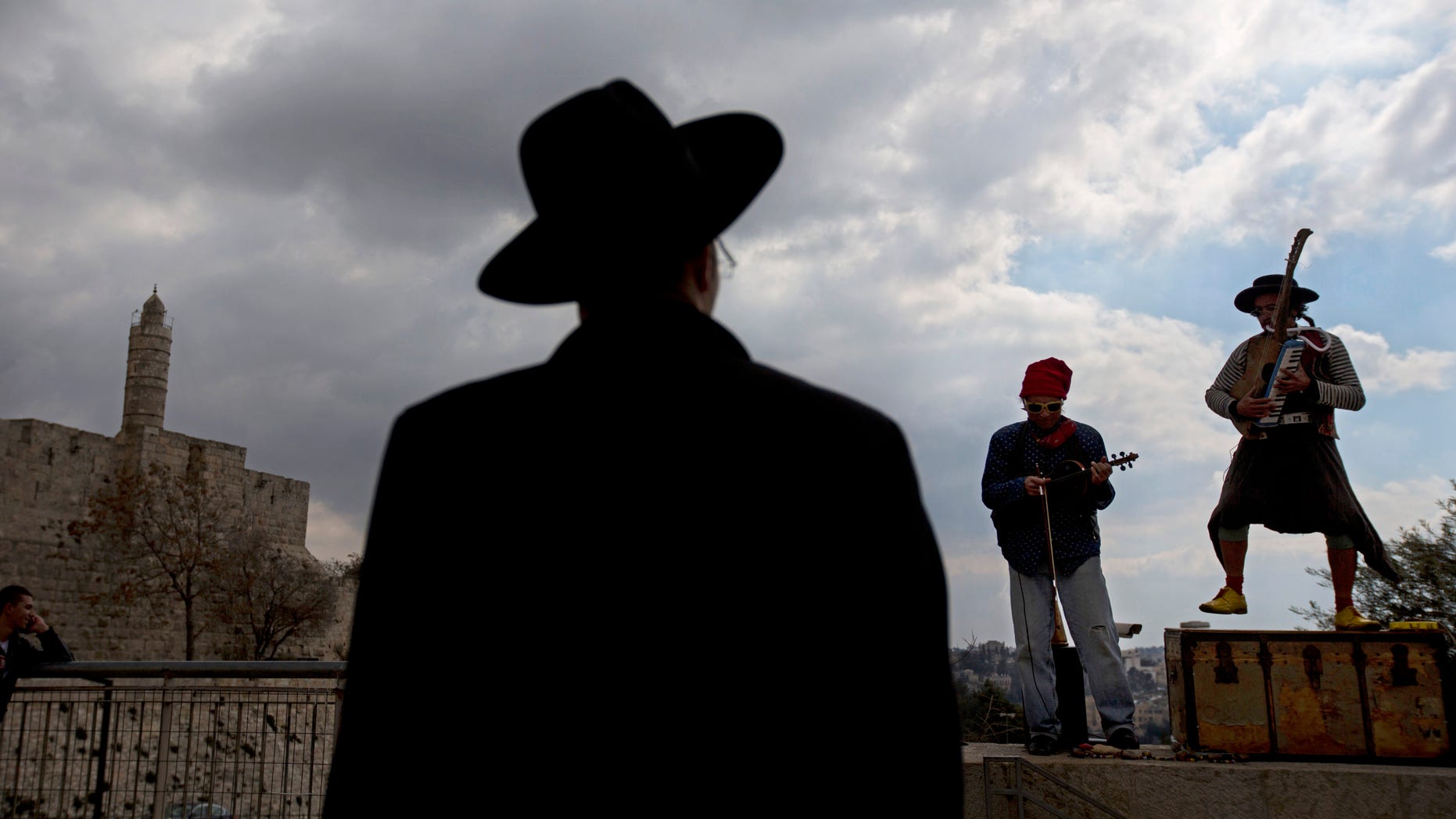 An ultra-Orthodox Jewish man looks at street performers as the play music near the Tower of David in Jerusalem's old city, Thursday, Feb. 6, 2014. (AP Photo/Sebastian Scheiner)