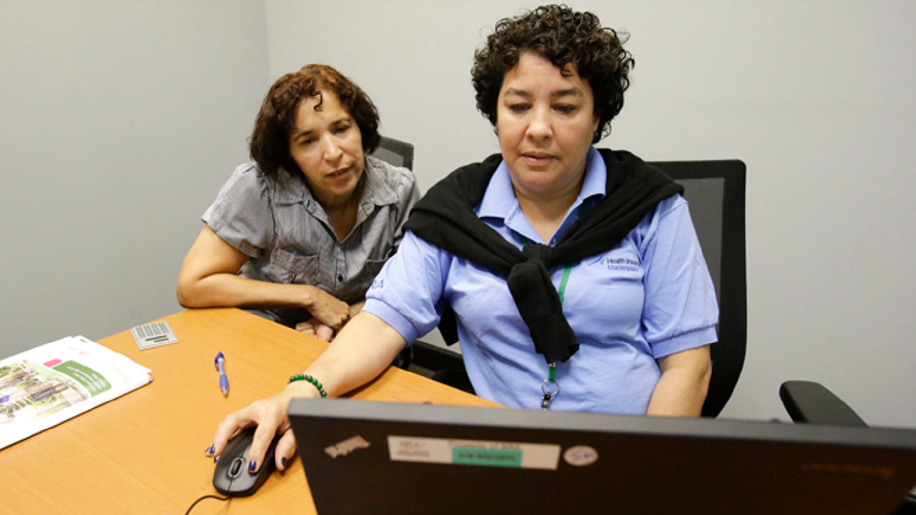 FILE - In this Nov. 17, 2014 file photo, Maria Arias, left, gets help from navigator Yvette Frias, as she signs up for the Affordable Care Act at the Orlando Enrollment Assistance Center, in Orlando, Fla. Florida has eclipsed California to become the state with the highest number of consumers buying health coverage through new insurance markets under the Affordable Care Act, according to federal statistics released Wednesday, Feb. 18, 2015. (AP Photo/John Raoux, File)