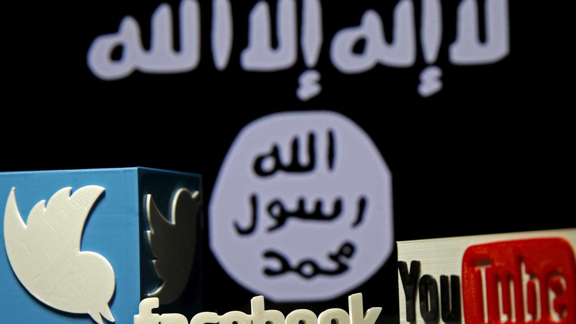 File photo: 3D plastic representations of the Twitter, Facebook and Youtube logos are seen in front of a displayed ISIS flag in this photo illustration shot February 3, 2016. (REUTERS/Dado Ruvic)