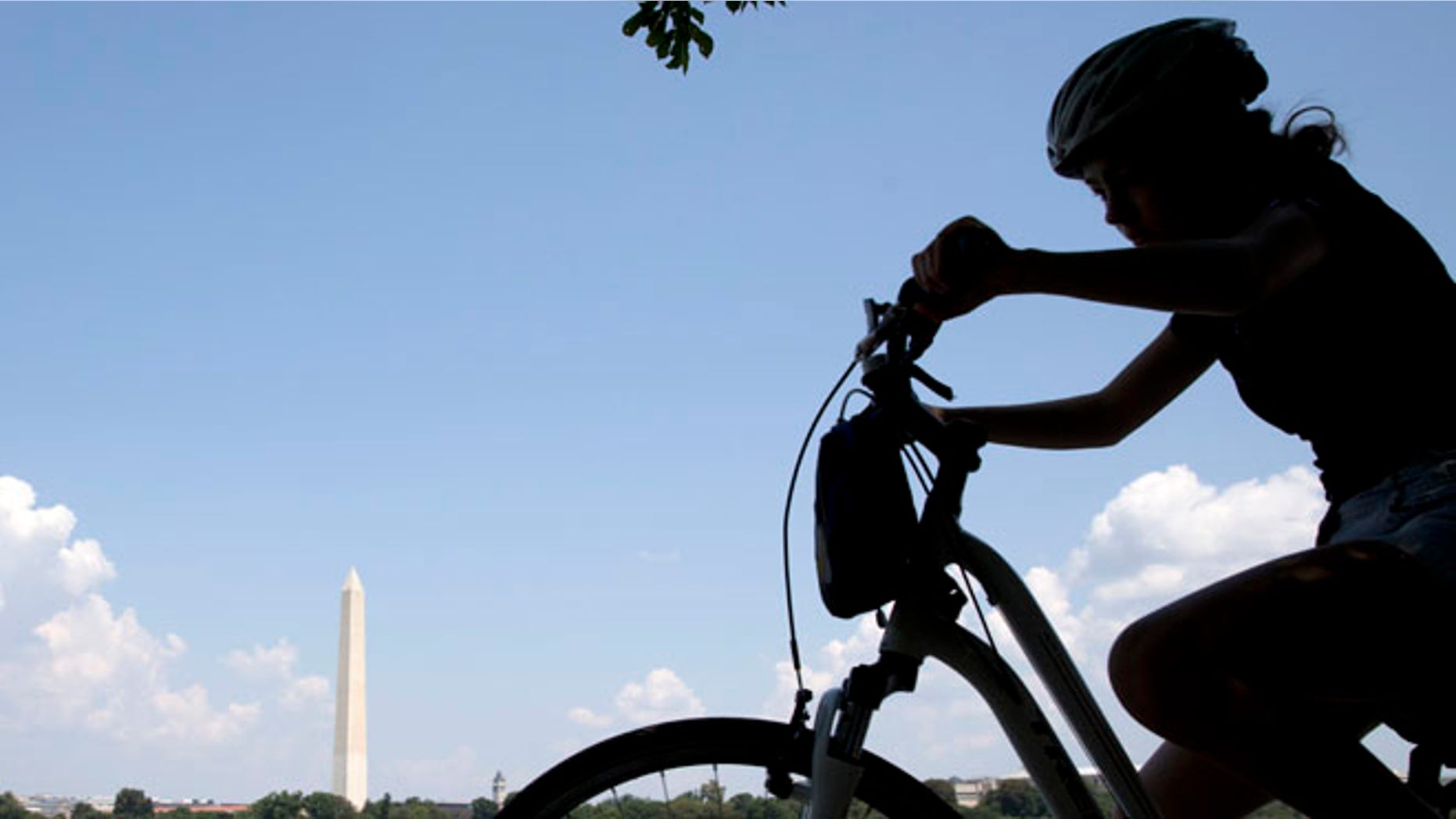 Aug. 17, 2015: A girl on a bicycle pedals around the Tidal Basin with the Washington Monument in the background.