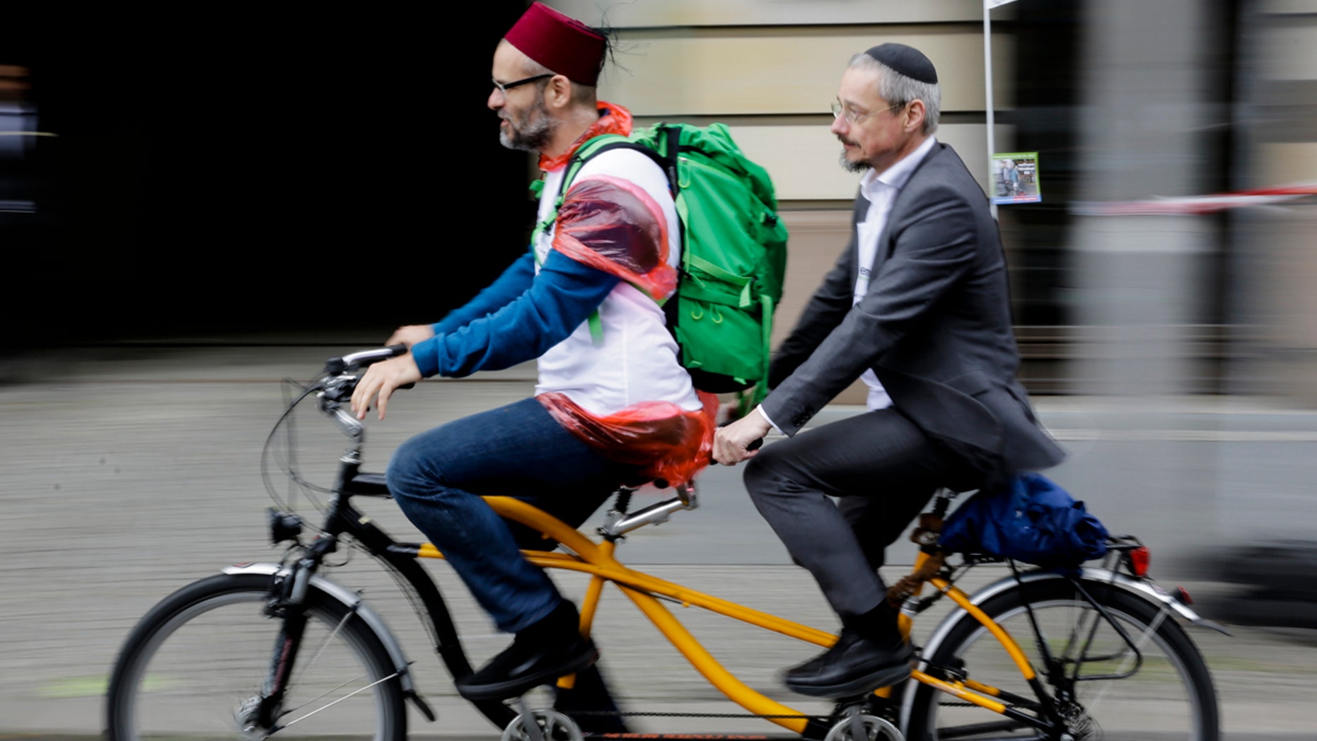 A Muslim and a Jewish man rides a tandem together during a bicycle tandem tour of Jews and Moslems against anti-Semitism and hatred of Muslims in Berlin, Sunday, June 24, 2018. (AP Photo/Markus Schreiber)