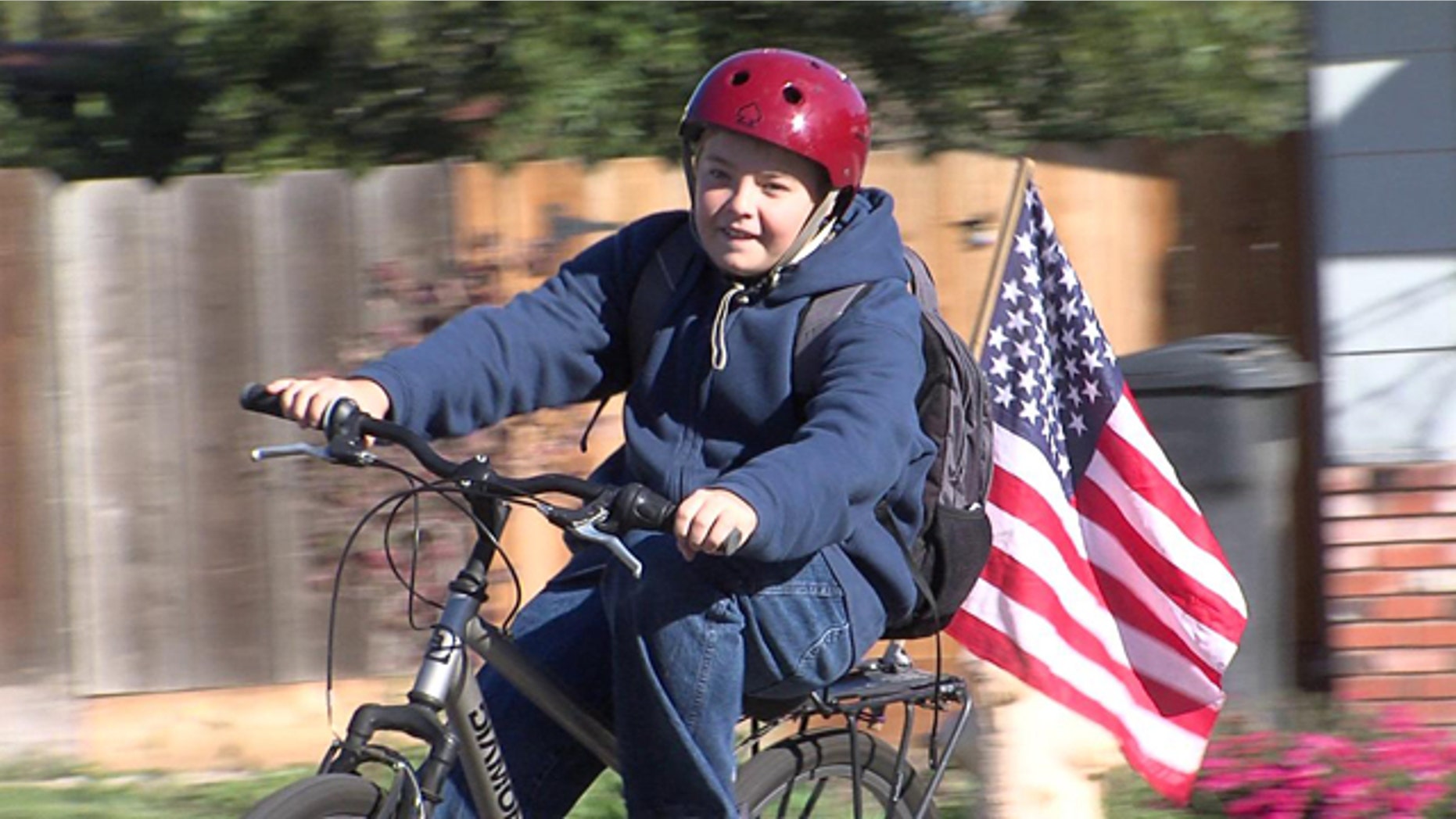 Cody Alicea, 13, rides his bicycle with his American Flag attached.