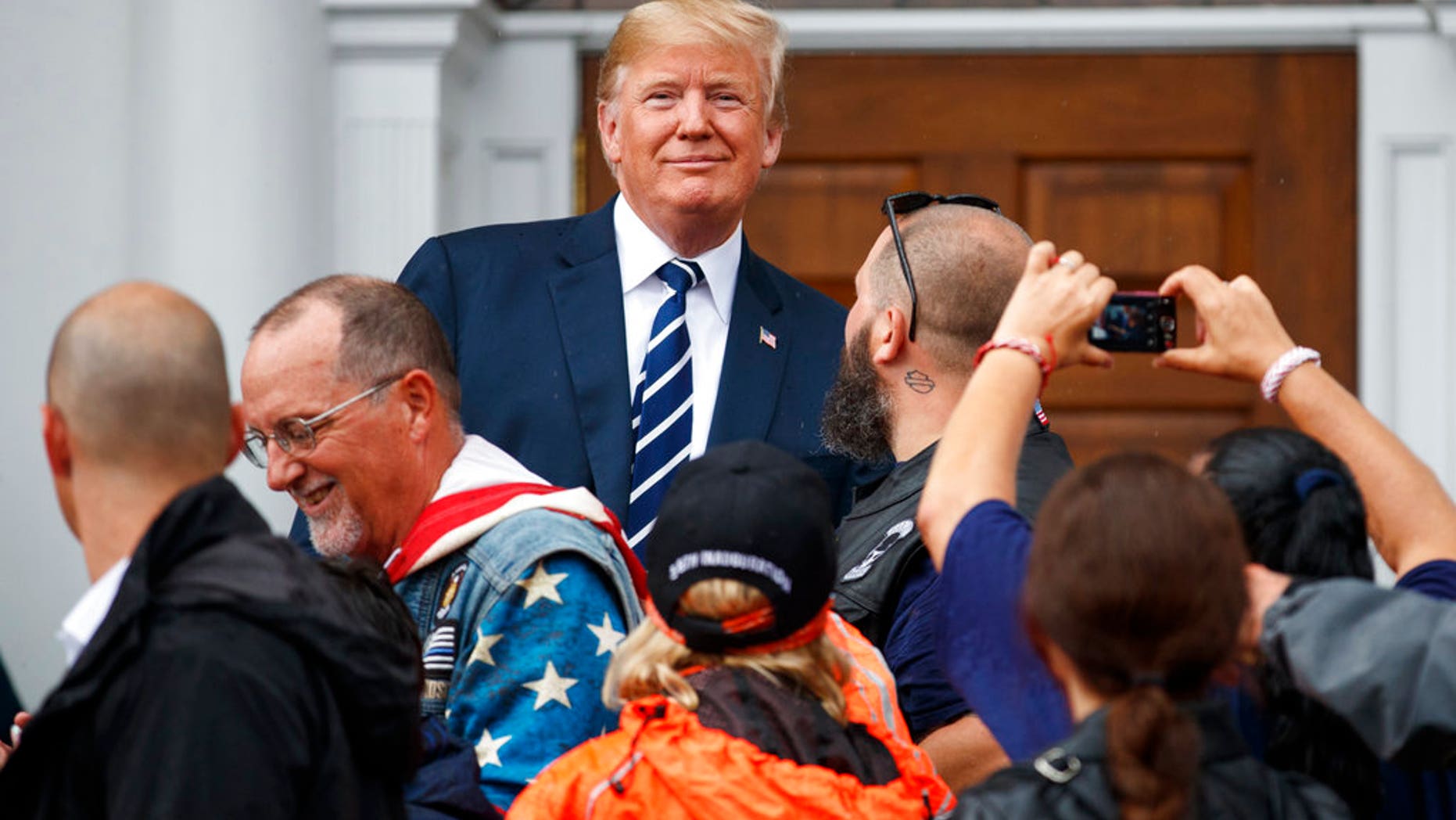 President Donald Trump visits with members of Bikers for Trump and supporters, Saturday, Aug. 11, 2018, outside the clubhouse of Trump National Golf Club in Bedminster, N.J. (AP Photo/Carolyn Kaster)