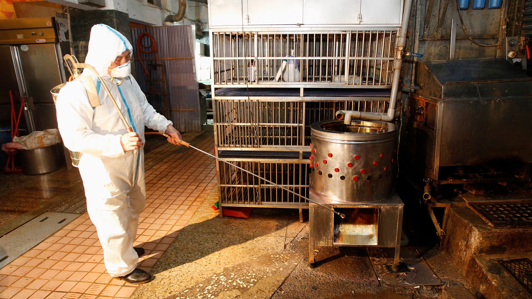 A janitor sprays disinfectant at empty chicken cages in a traditional market in New Taipei city April 29, 2013.